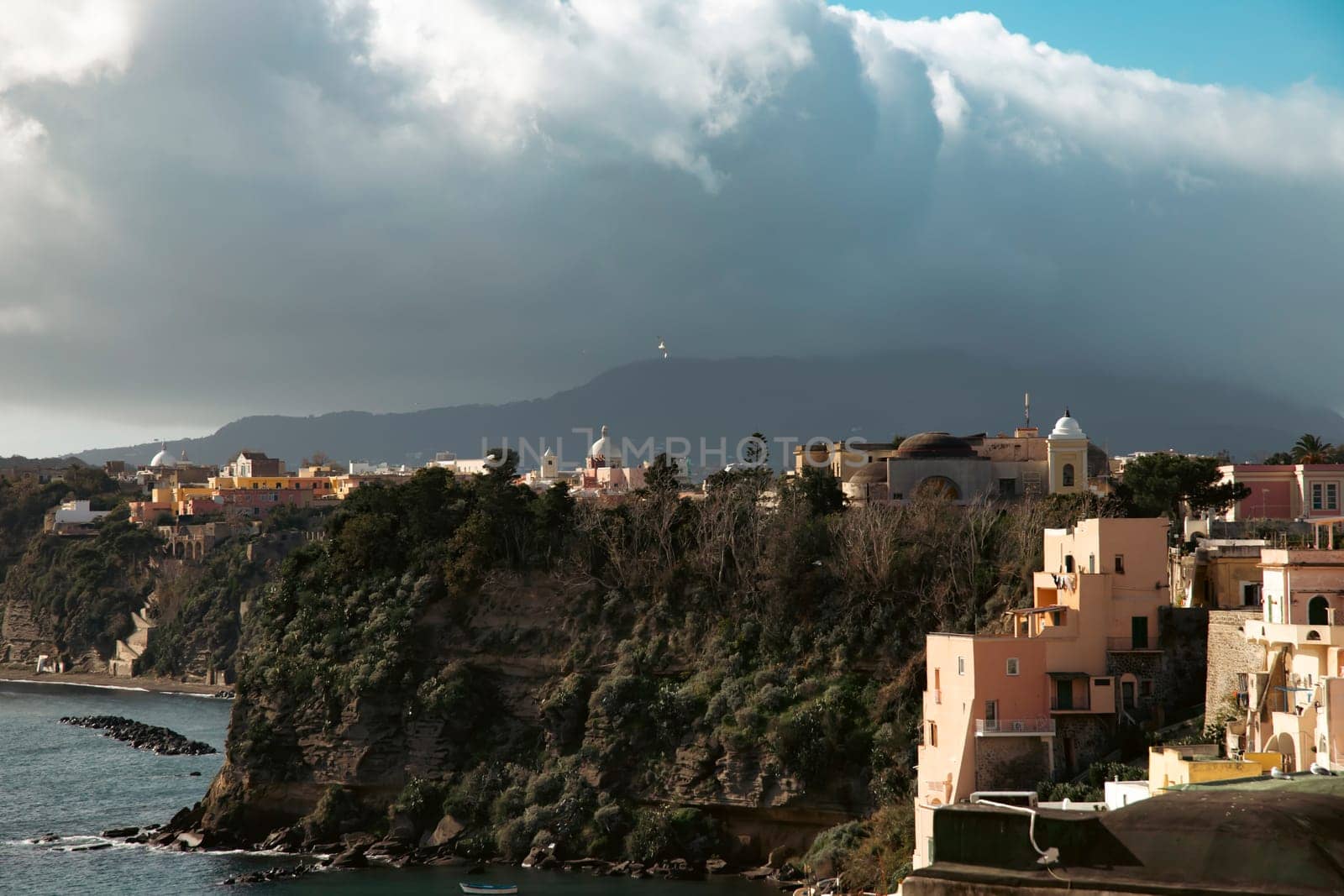View of the Port of Corricella with lots of colorful houses on a sunny day in Procida Island, Italy.