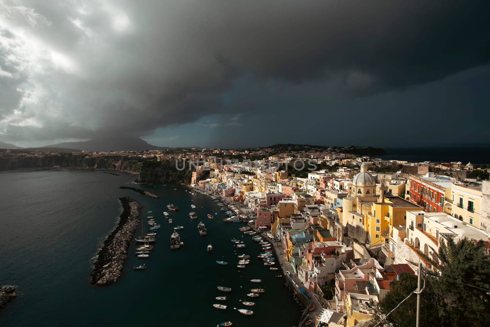 View of the Port of Corricella with lots of colorful houses on a sunny day in Procida Island, Italy.