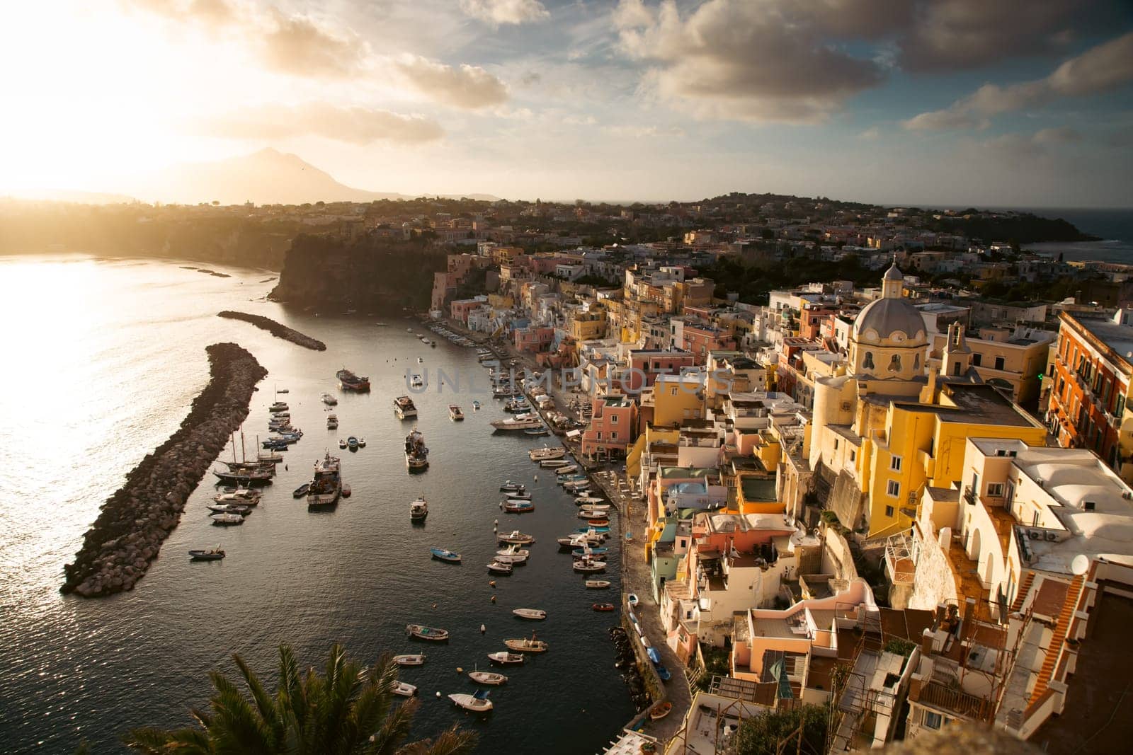View of the Port of Corricella with lots of colorful houses in the sunset, Procida Island, Italy.