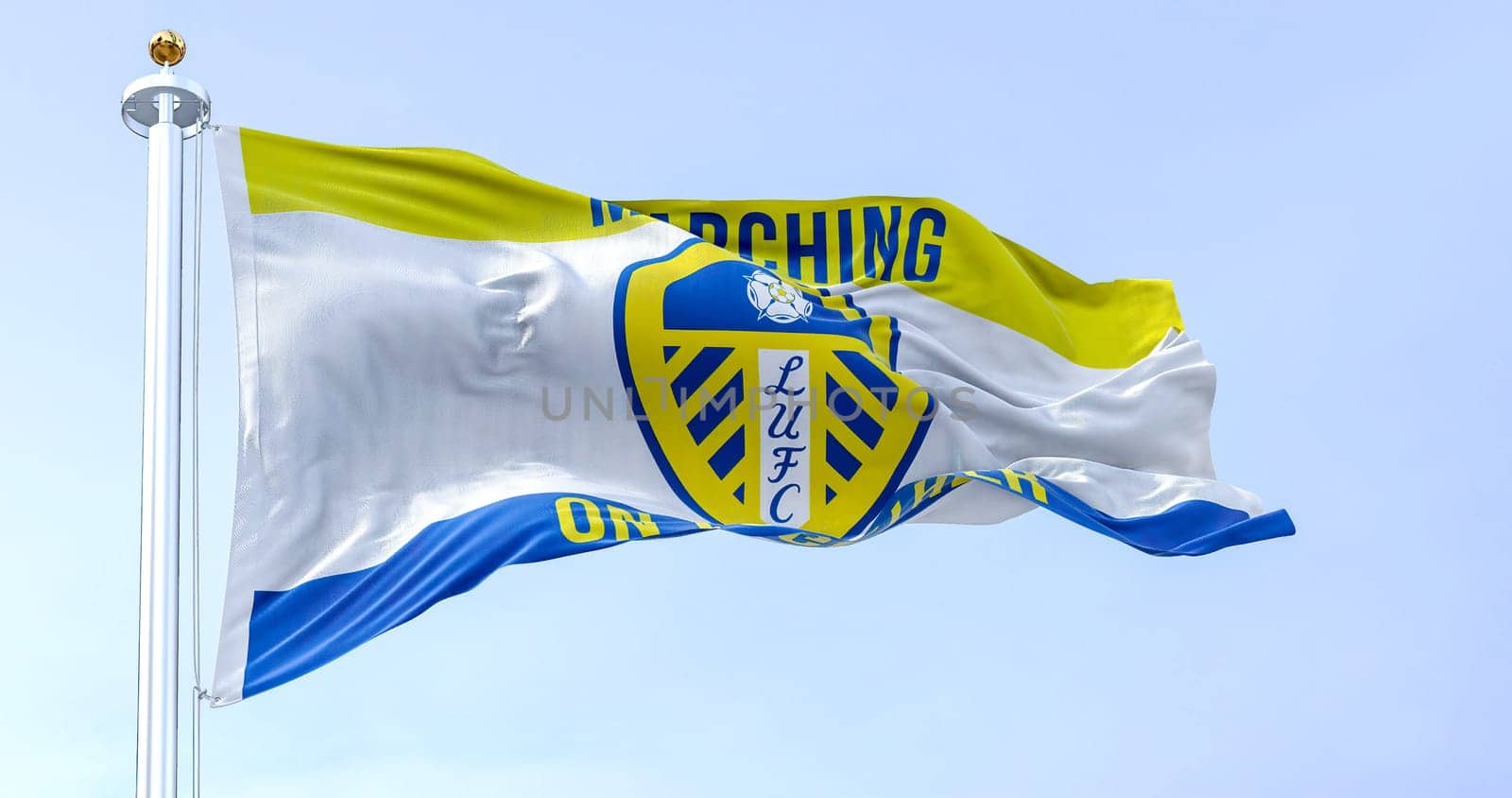 Leeds, UK, Oct. 2022: The Leeds United flag waving in the wind. White shield with blue and yellow stripes, white rose, and LUFC in blue. Rippled fabric. Realistic 3D illustration render.