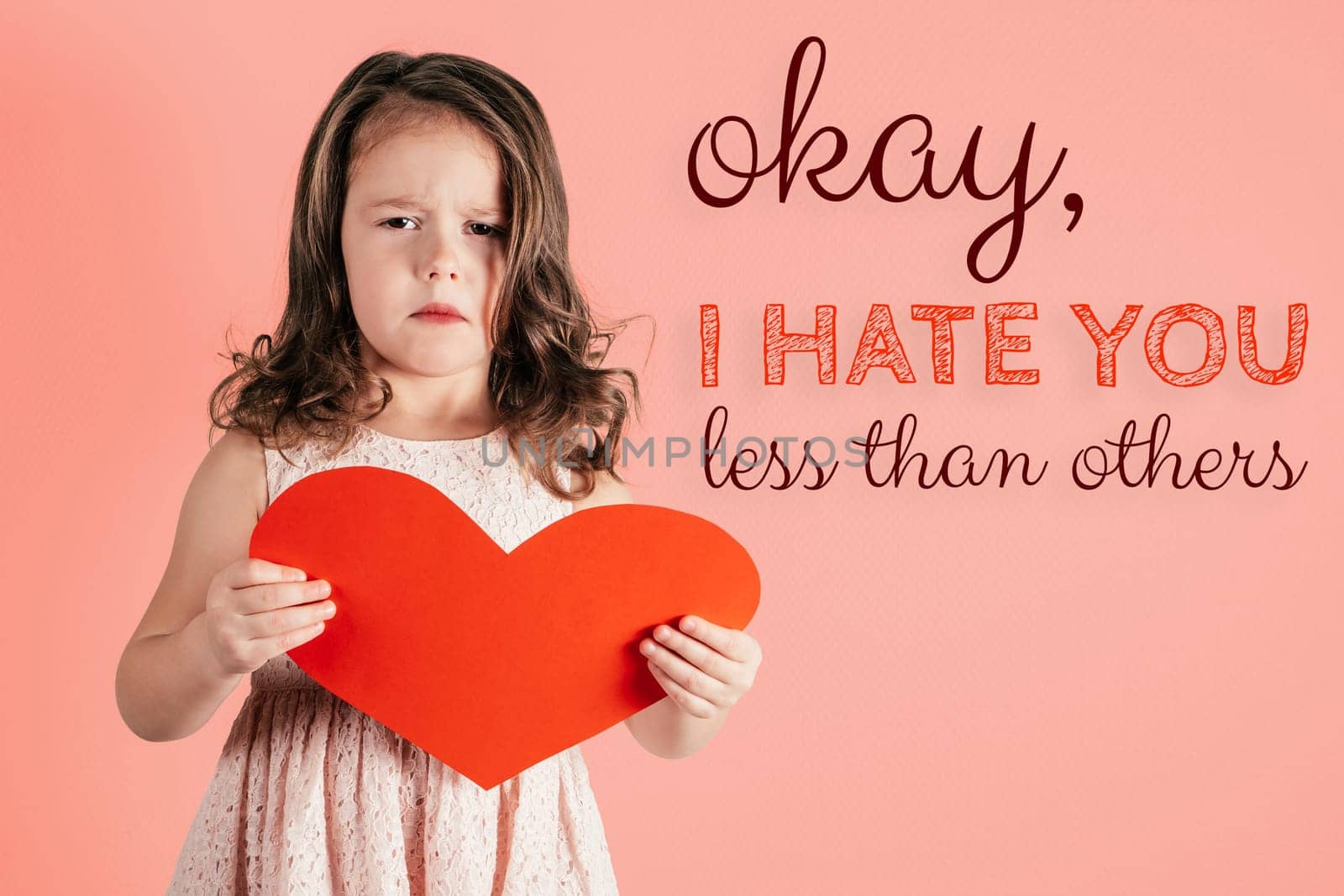 Cute little girl with long curly hair hold in hands big red paper heart showing discontent on peach background. Postcard, family holiday, Valentine's day, birthday, Mother's day concept. Copy space.