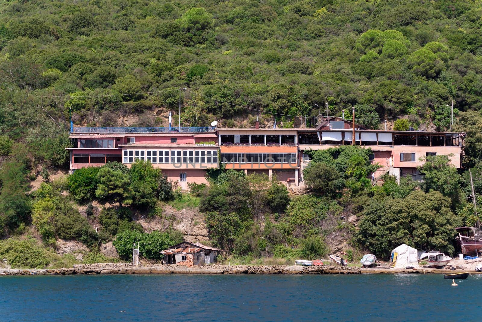 View from the sea of the green mountains of the European side of Bosphorus strait, with traditional buildings and dense trees in a summer day
