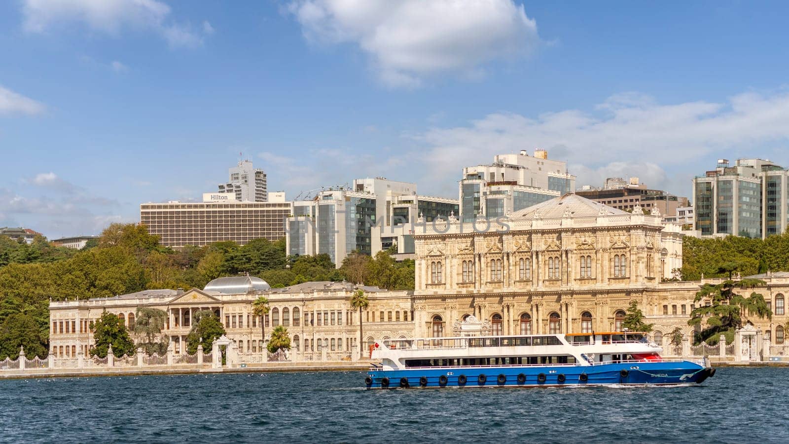 Ferry boat passing by Dolmabahce Palace, in Besiktas district of Istanbul, Turkey, on the European coast of the Bosporus strait, main administrative center of the Ottoman Empire formerly