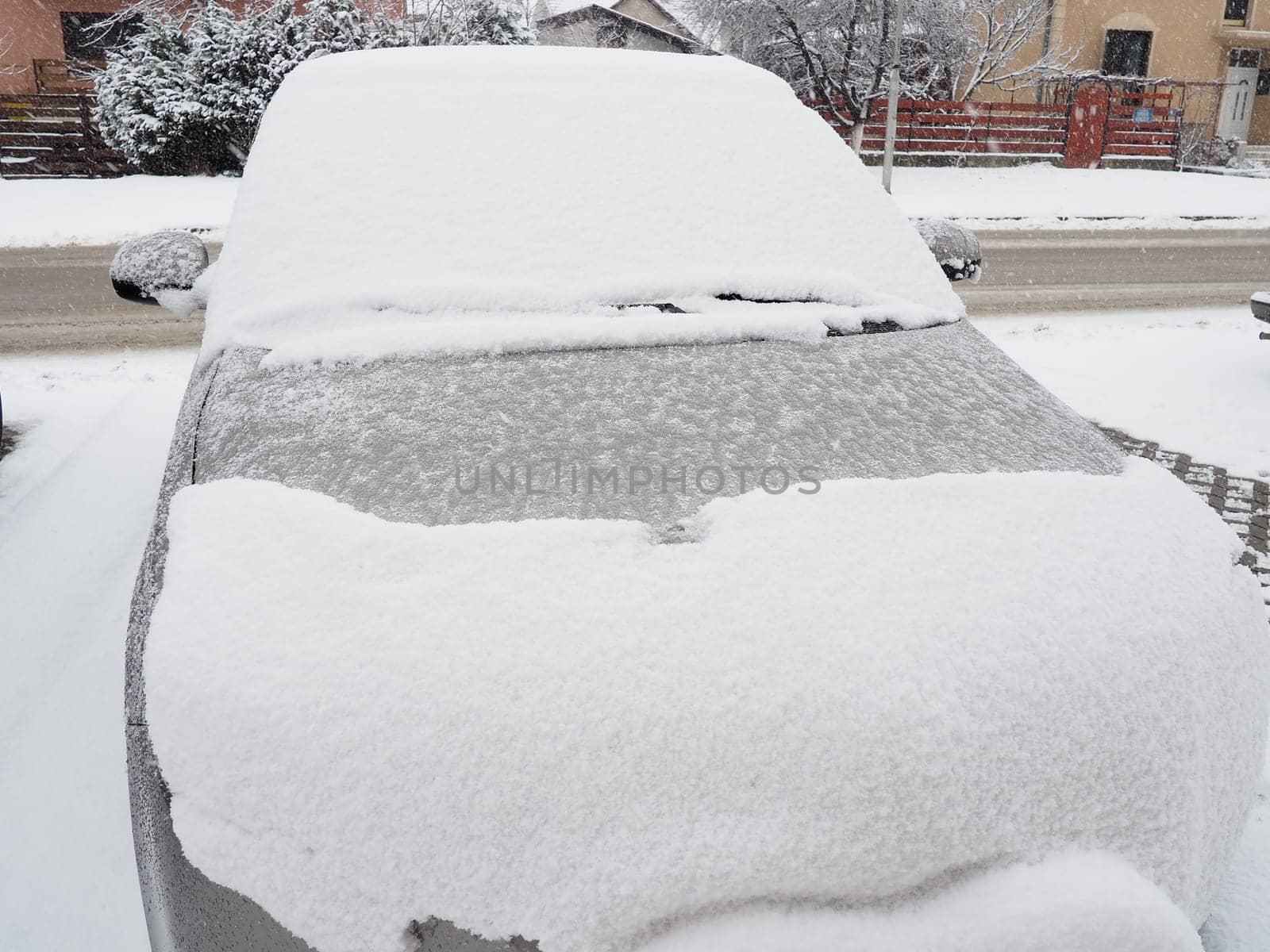 Snow and ice on the windshield, retrovisors and rear-view mirrors of the car. Winter driving conditions. Snow cleaning. Road traffic in winter. Metallic car. Snowdrifts and slush