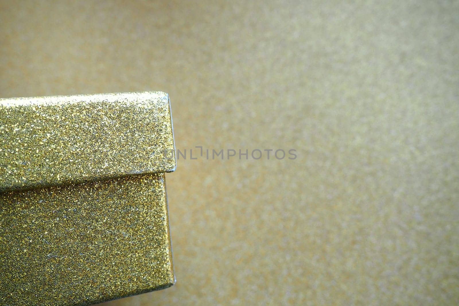 Golden gift box on a golden background. Decorative surprise box. Copy space.