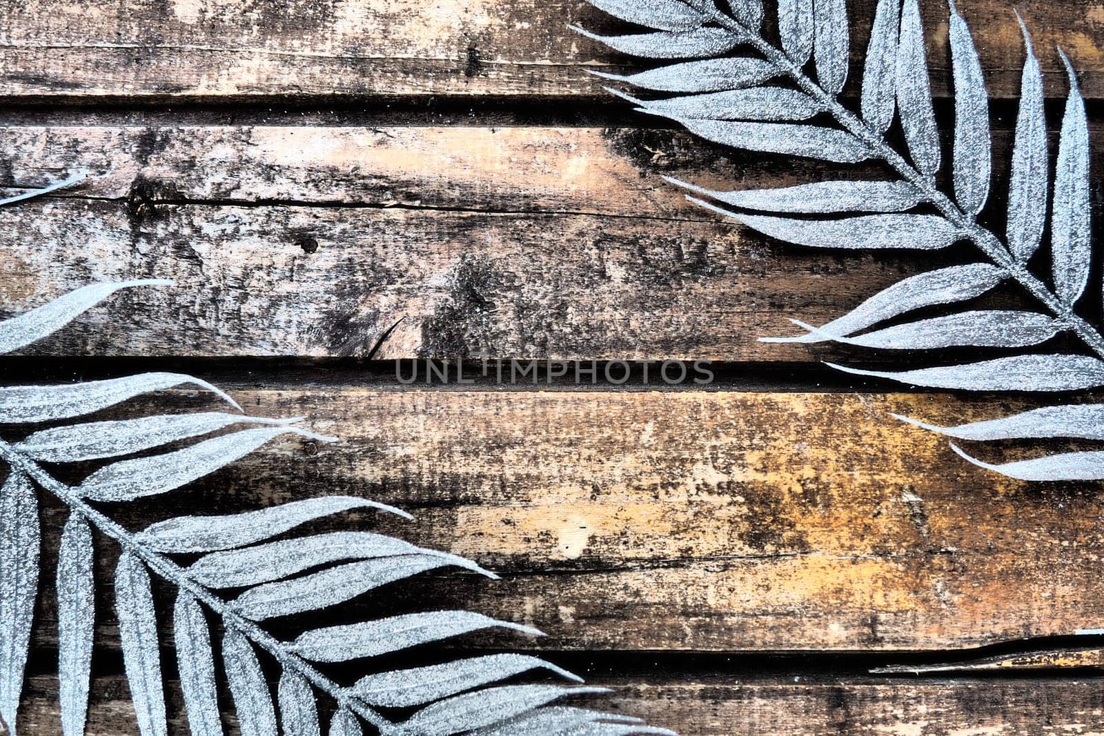 Wooden background from horizontal narrow boards. Two exotic tropical branches with thin palm leaves are located at the edges of the image. Background with copy space.