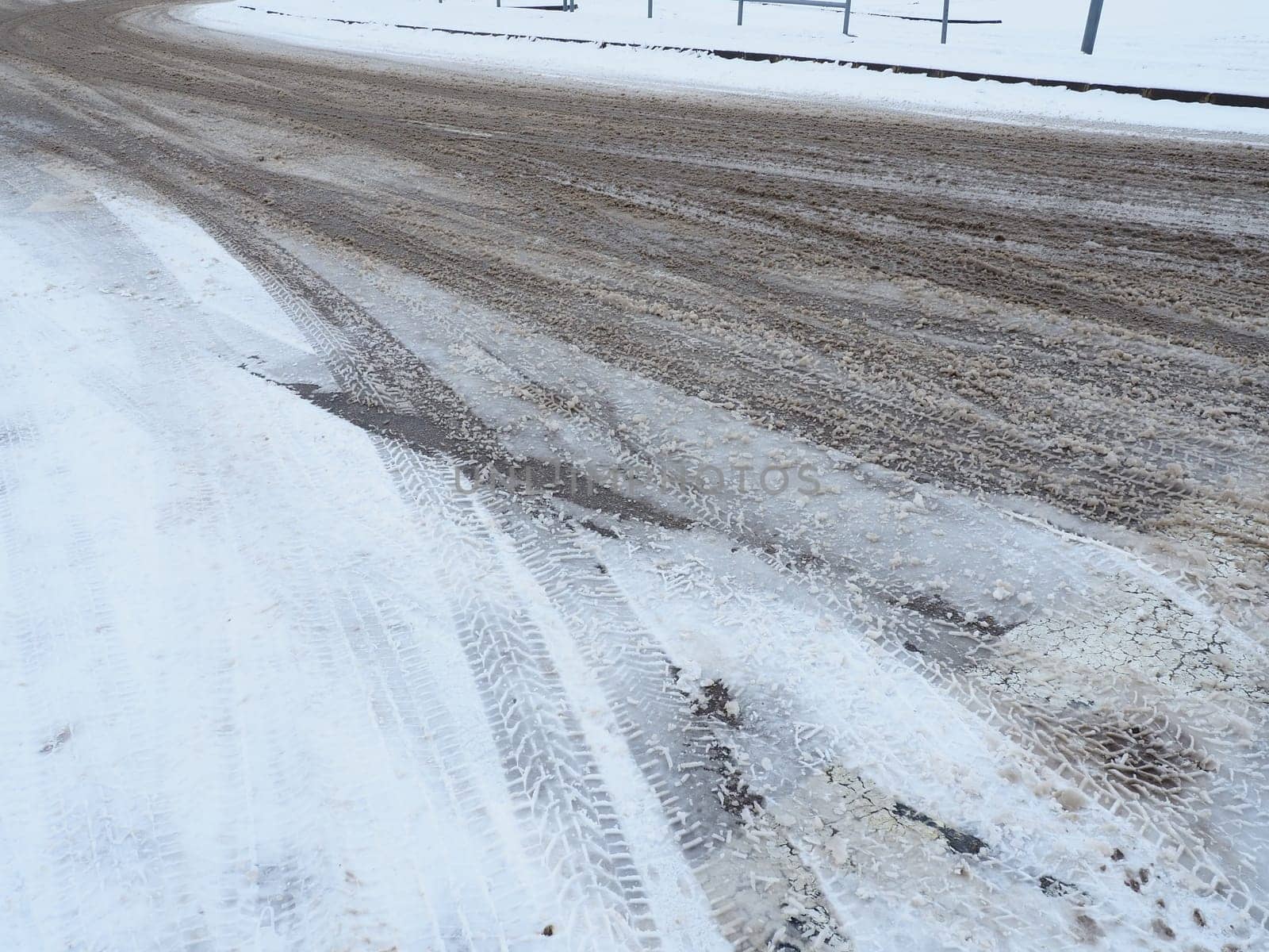 A fork or siding from a roundabout. Snowdrifts on the side of the road. Bad weather and traffic. Snow on asphalt. Difficult driving conditions. Winter slosh on the road. Braking distance of a car.