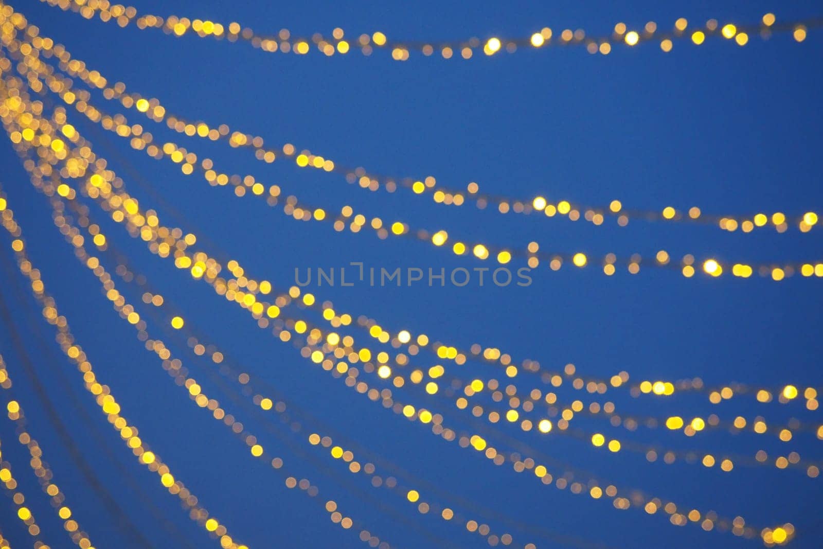 Yellow garlands against the evening sky. Defocused bokeh. New Year's and Christmas