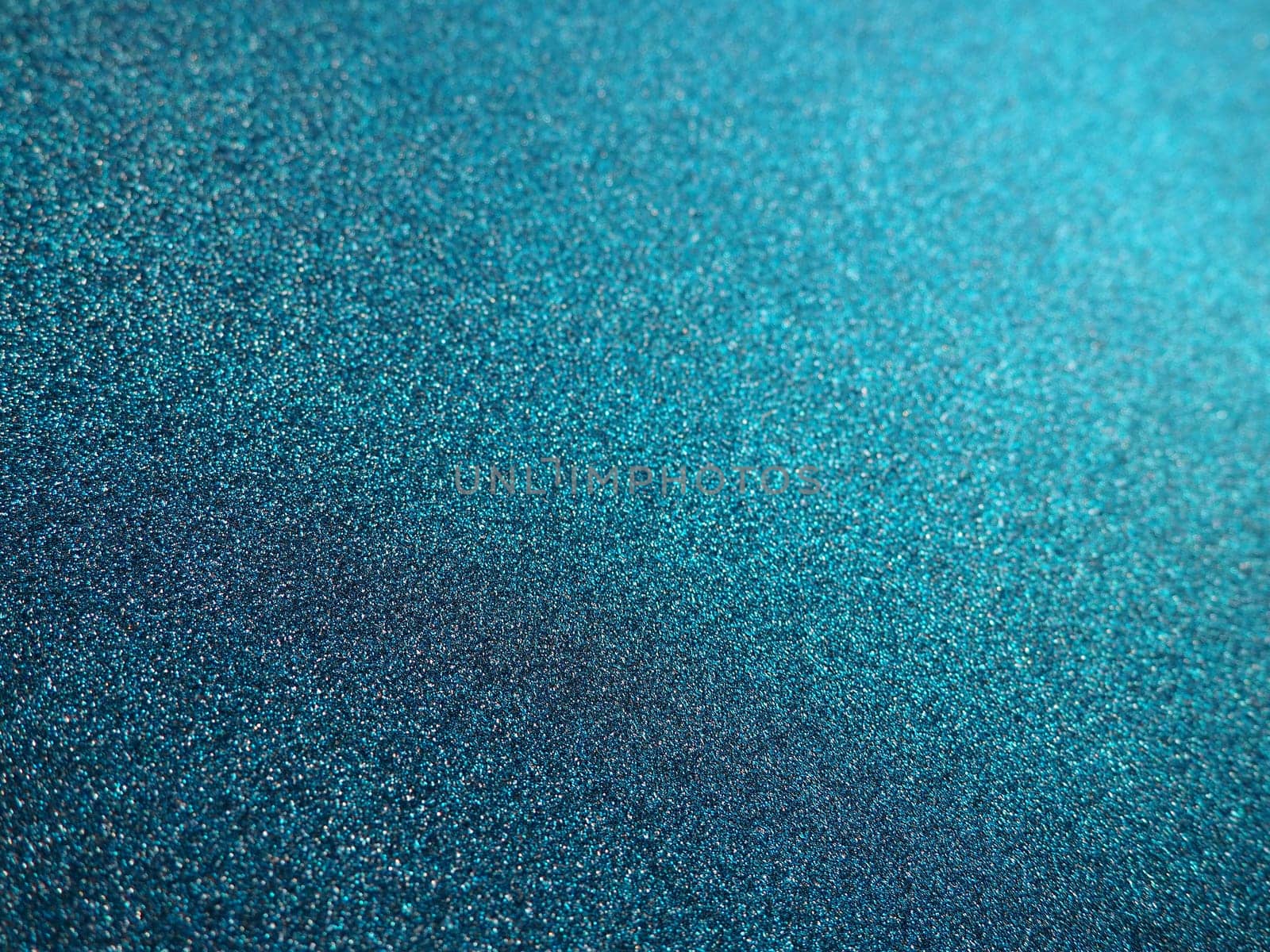 Deep blue. Texture of rough paper or cardboard. Defocused bokeh sparkles and shining. Festive blue background with illuminated sapphire gradient.