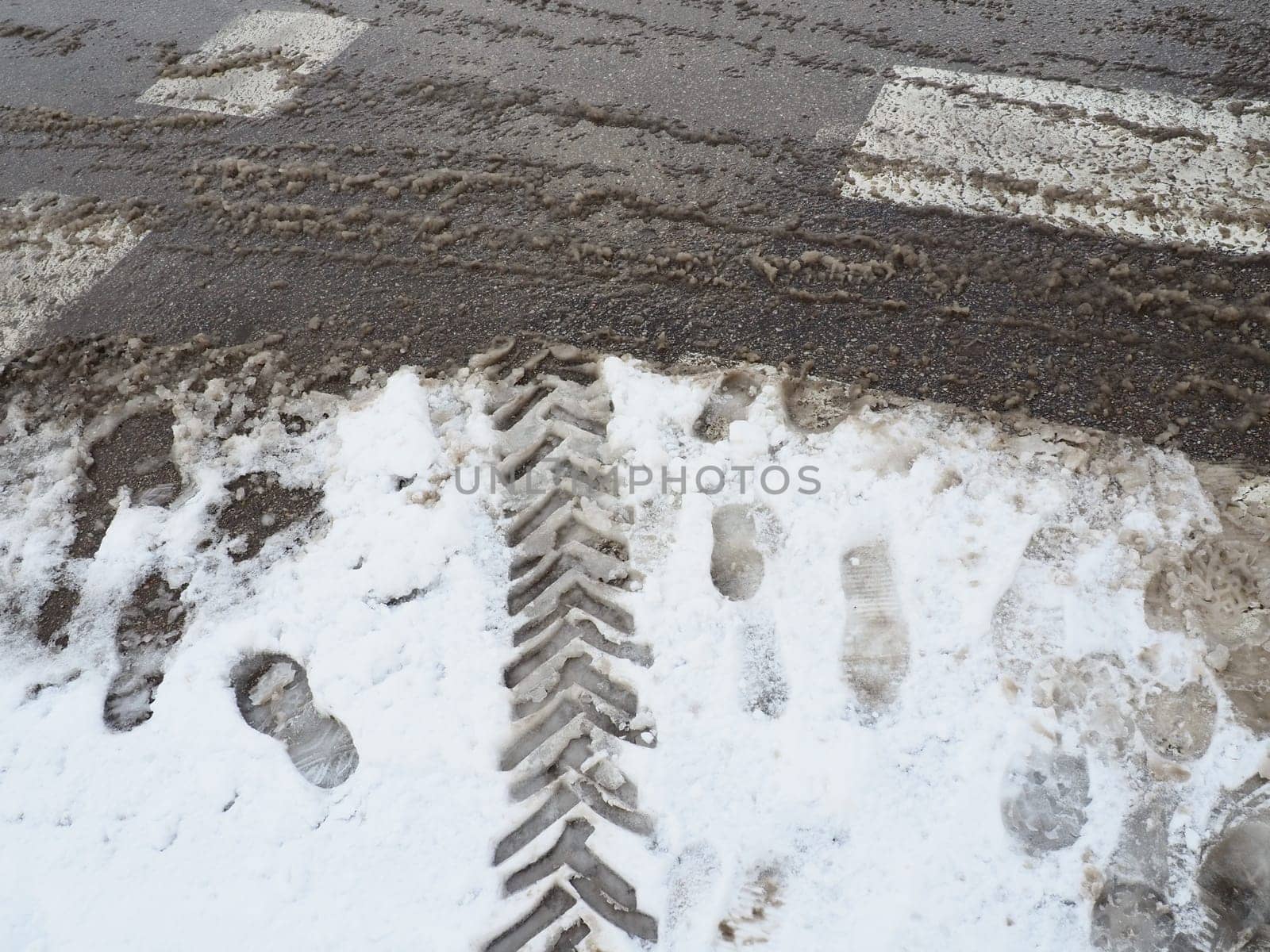A fork or siding from a roundabout. Snowdrifts on the side of the road. Bad traffic weather. Footprints in the snow. Difficult driving conditions. Winter slosh on the road. Braking distance of a car