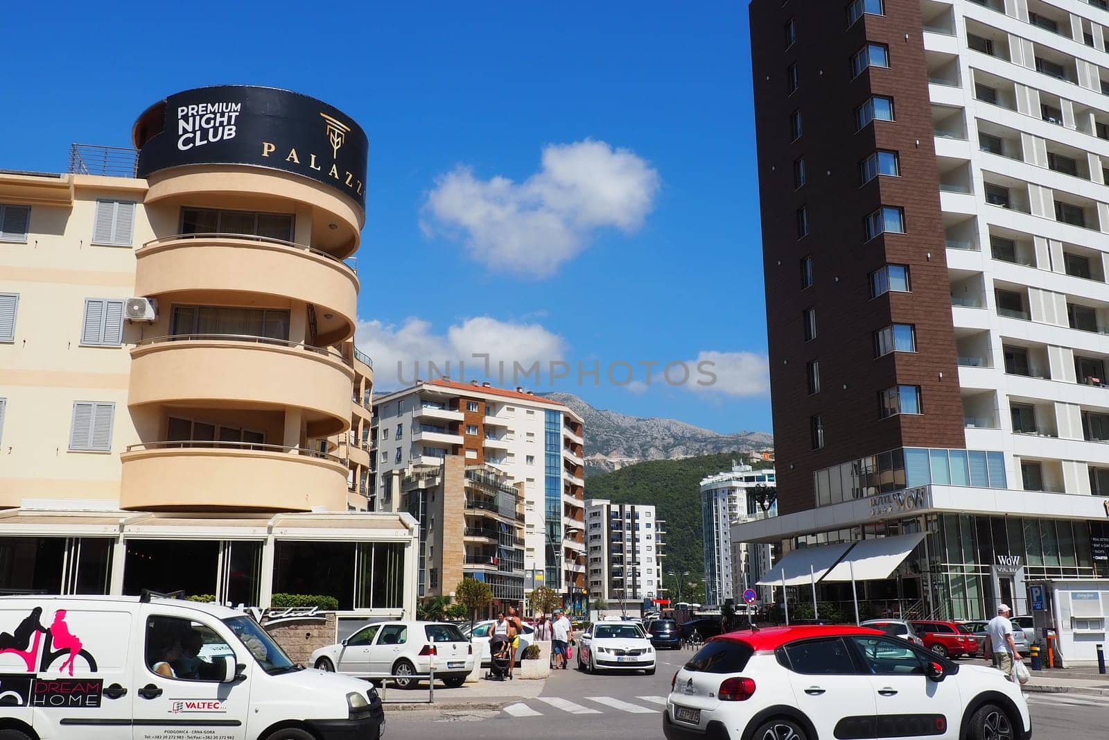 Budva, Montenegro, August 18, 2022. City life of Budva in the summer tourist season. Modern buildings, transport, people on the street go shopping, cafes. Sunny day. Tourism and active lifestyle