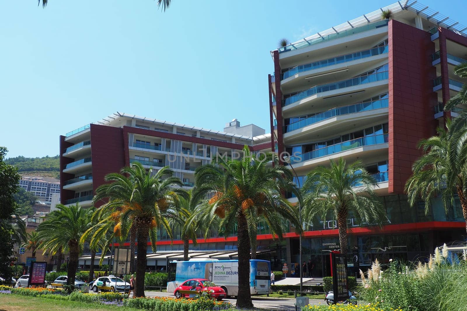 Budva, Montenegro, August 18, 2022. City life of Budva in the summer tourist season. Modern buildings, transport, people on the street go shopping, cafes. Sunny day. Tourism and active lifestyle