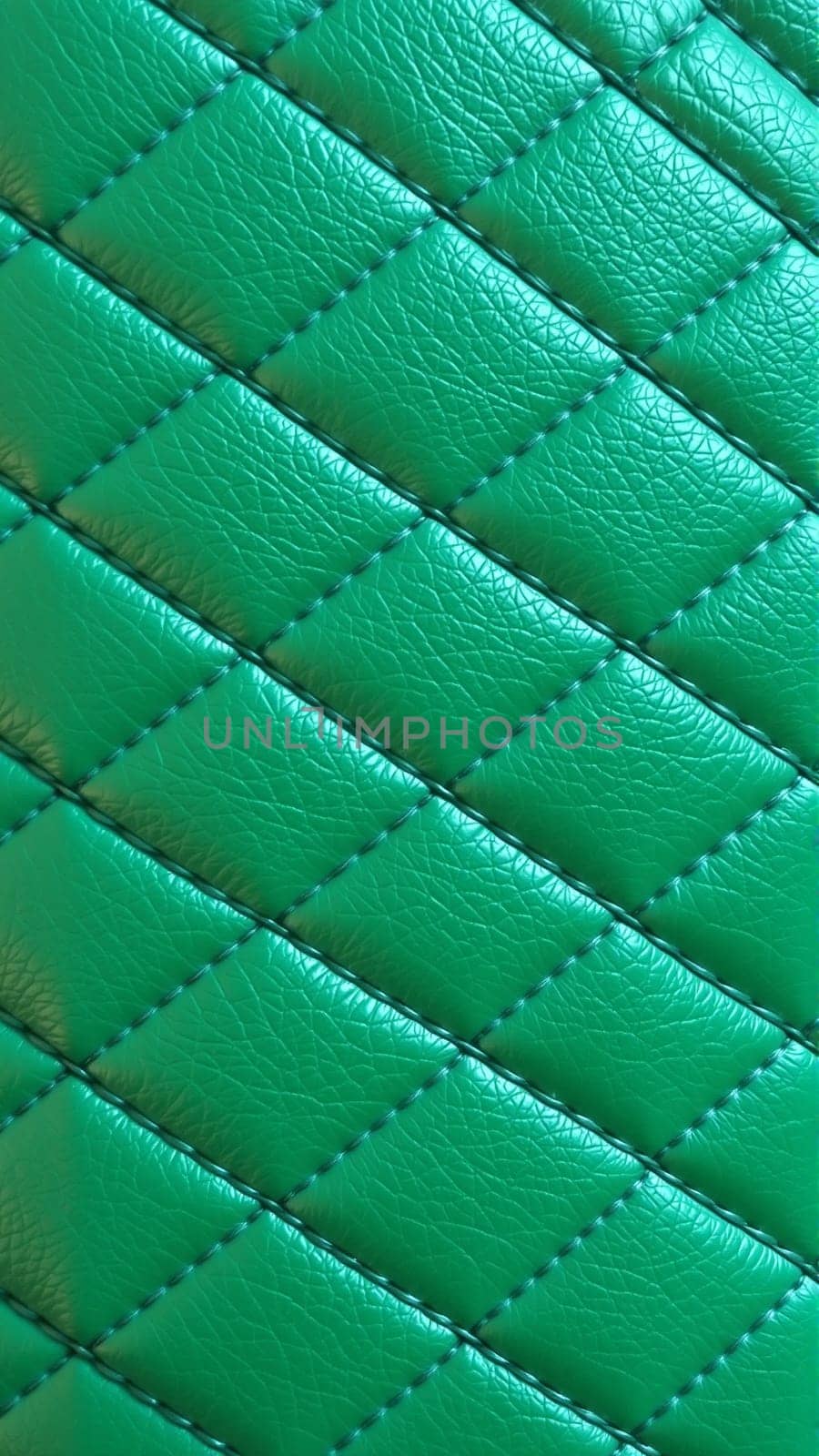 Green artificial leather surface texture, stitched in the form of rhombuses, squares, rectangles. Quilted eco-leather. High quality photo