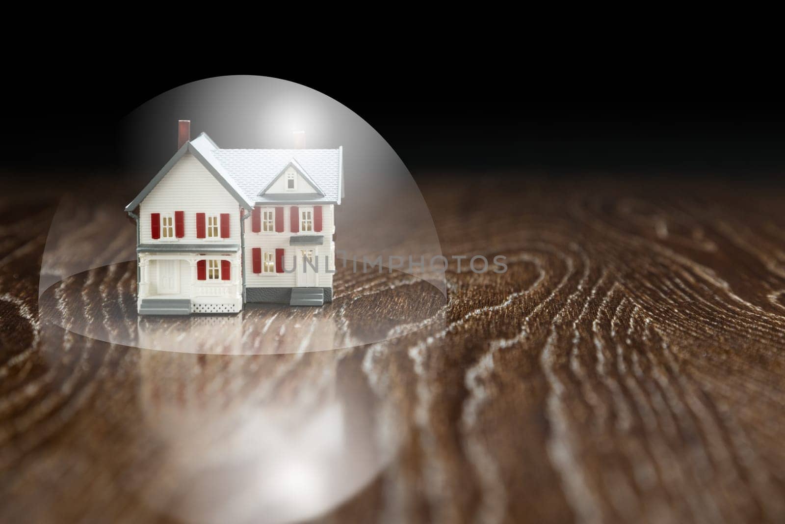 Model House on a Wooden Table Under a Protective Bubble.