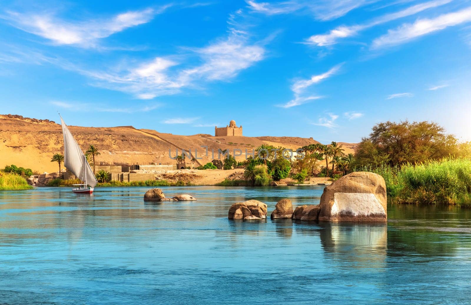 Nile riverbank near Aswan and traditional sailboat, Upper Egypt.