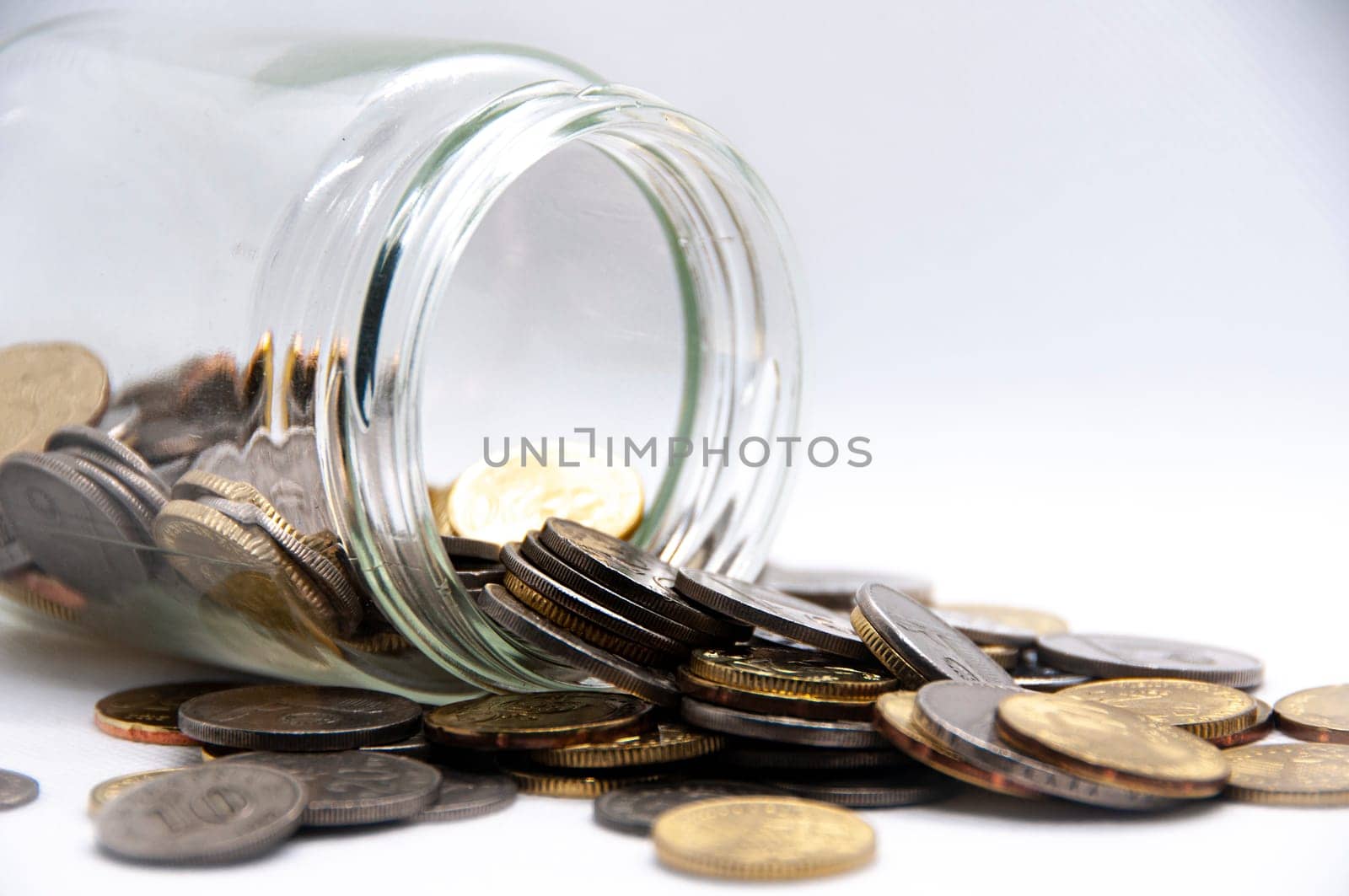 Close up of coins in a jar on white background with customizable space for text or ideas. Business and investment concept.