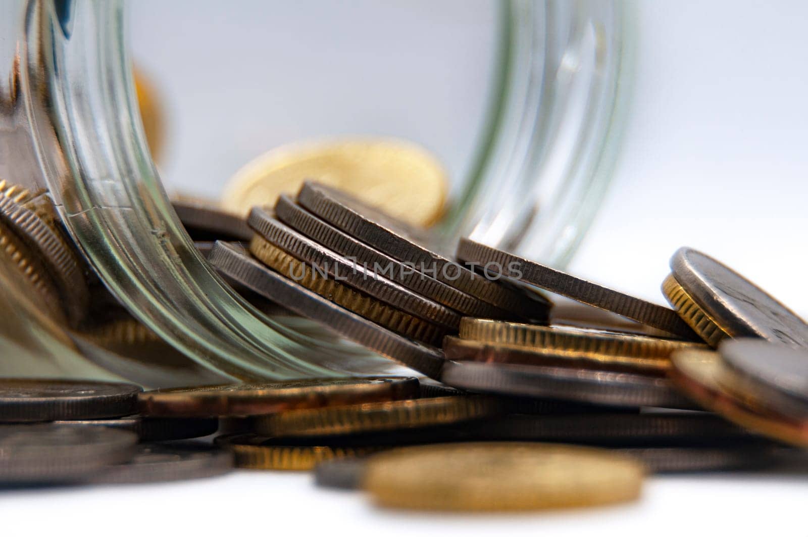 Close up of coins in a jar on white background with customizable space for text or ideas. Business and investment concept.