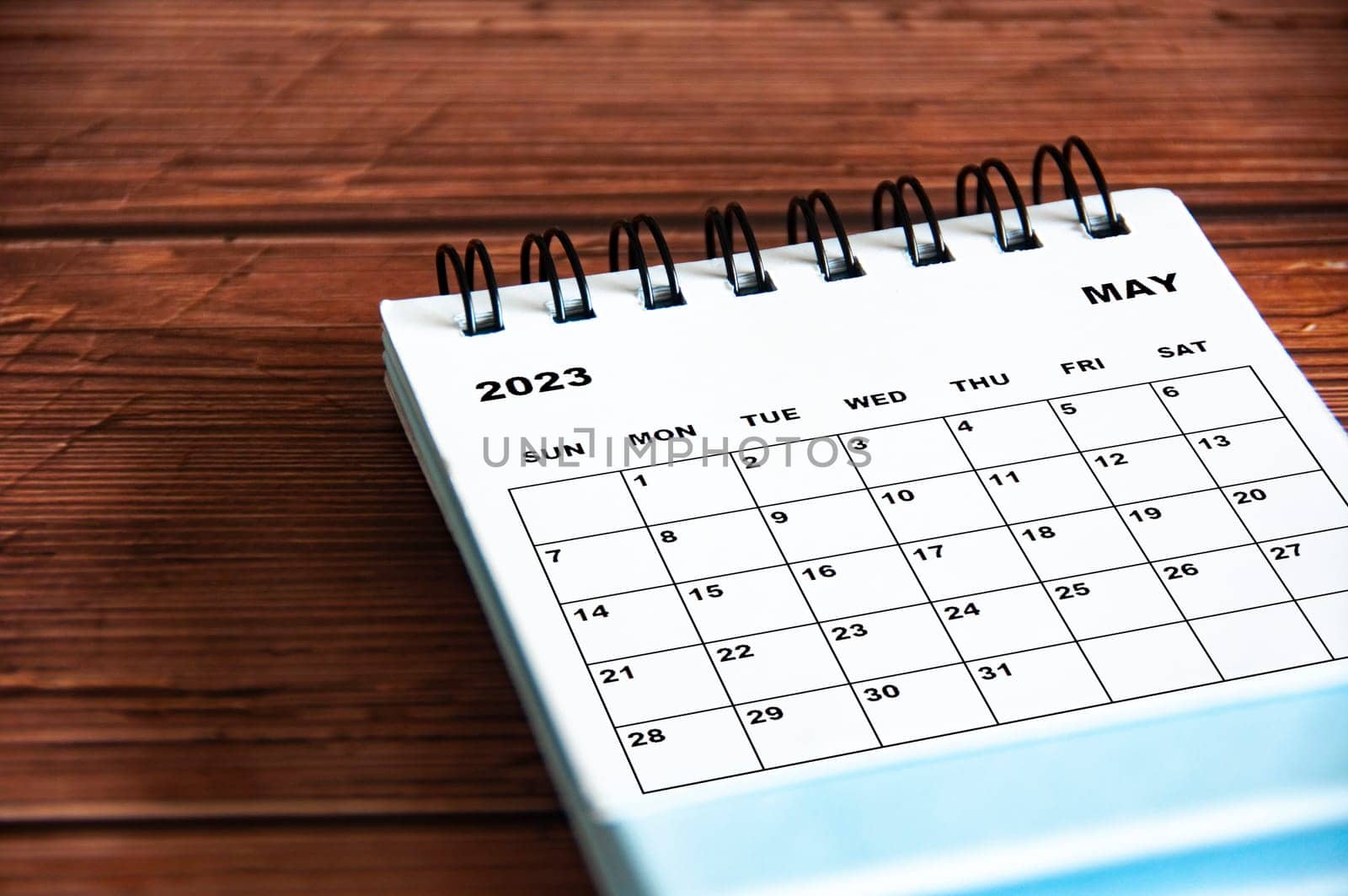 May 2023 white desk calendar on wooden table background.