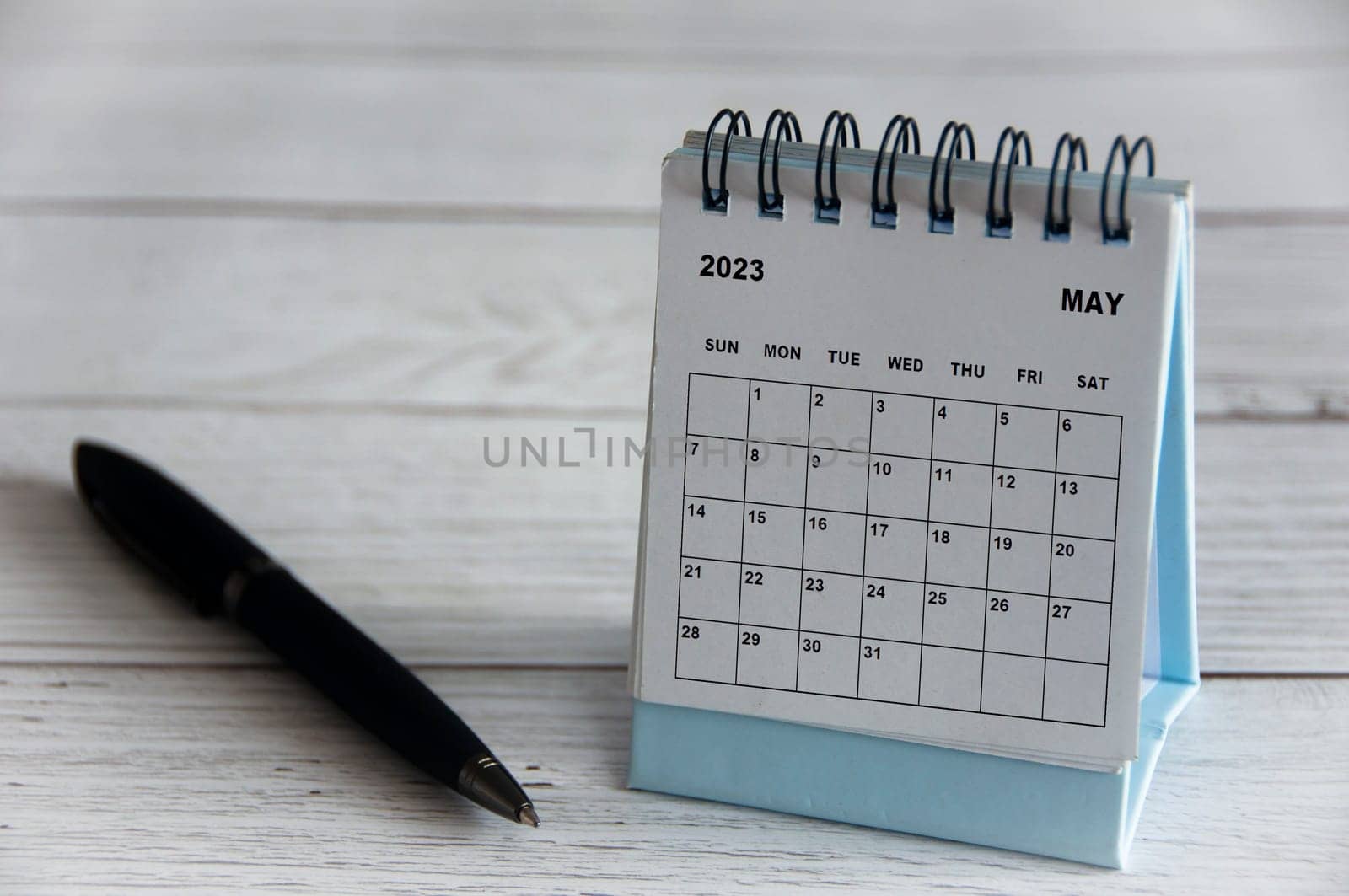 May 2023 white desk calendar with black pen on wooden table. Calendar concept