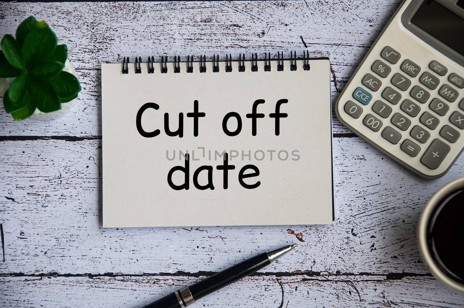 Cut off date text on notepad with table plant, calculator and pen background.