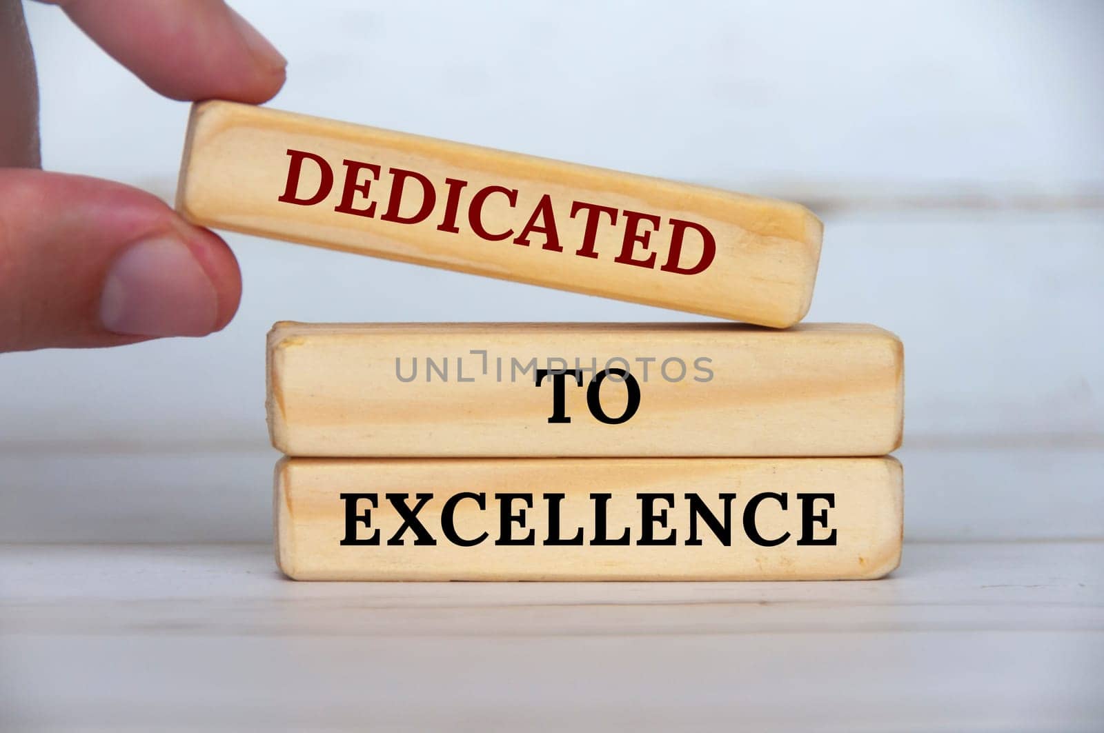 Dedicated to excellence text on wooden blocks with wooden cover background. Business motivation concept.