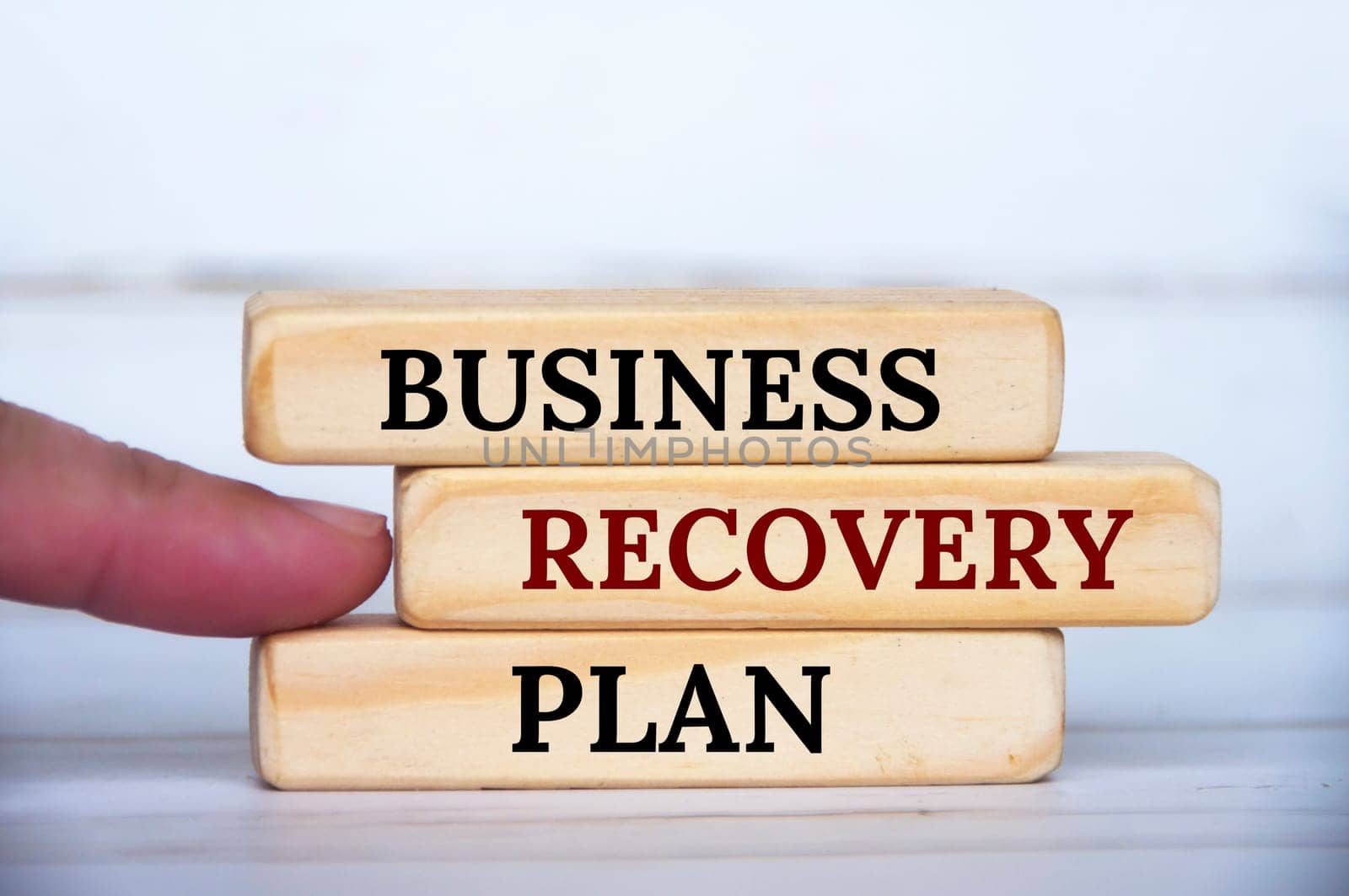 Finger pointing business recovery plan text on wooden blocks. Business recovery concept.