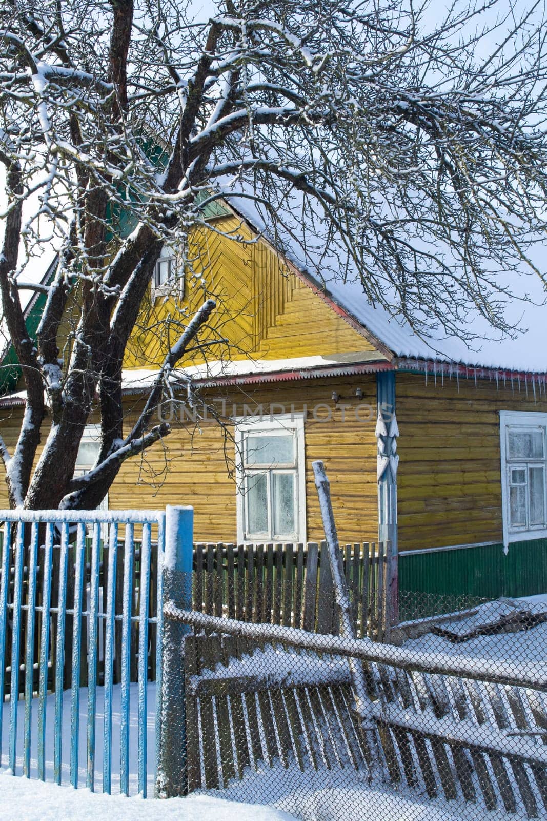 Beautiful wooden house covered with fresh snow. Old winter village cozy. Rural wintertime snowy landscape. Scenic countryside view. Vertical image