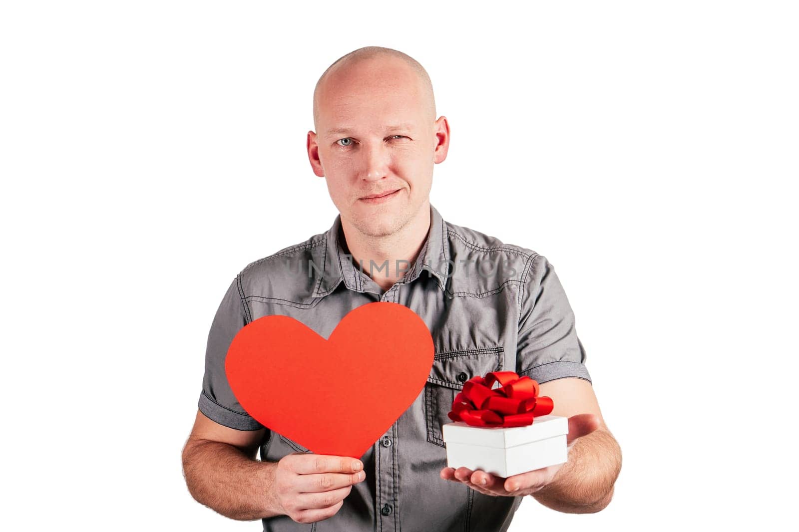 Smiling handsome bald middle-aged man in grey shirt hold big red paper heart and white gift box with red ribbon bow isolated on white background. Valentine's day, love, relations, emotion concept