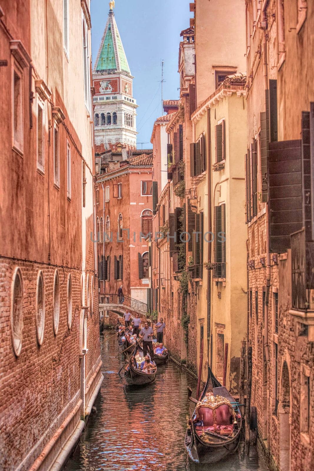 Gondoloas drift down thre canals with St. Marks, Campanile Tower, in the background, Venice, Italy.