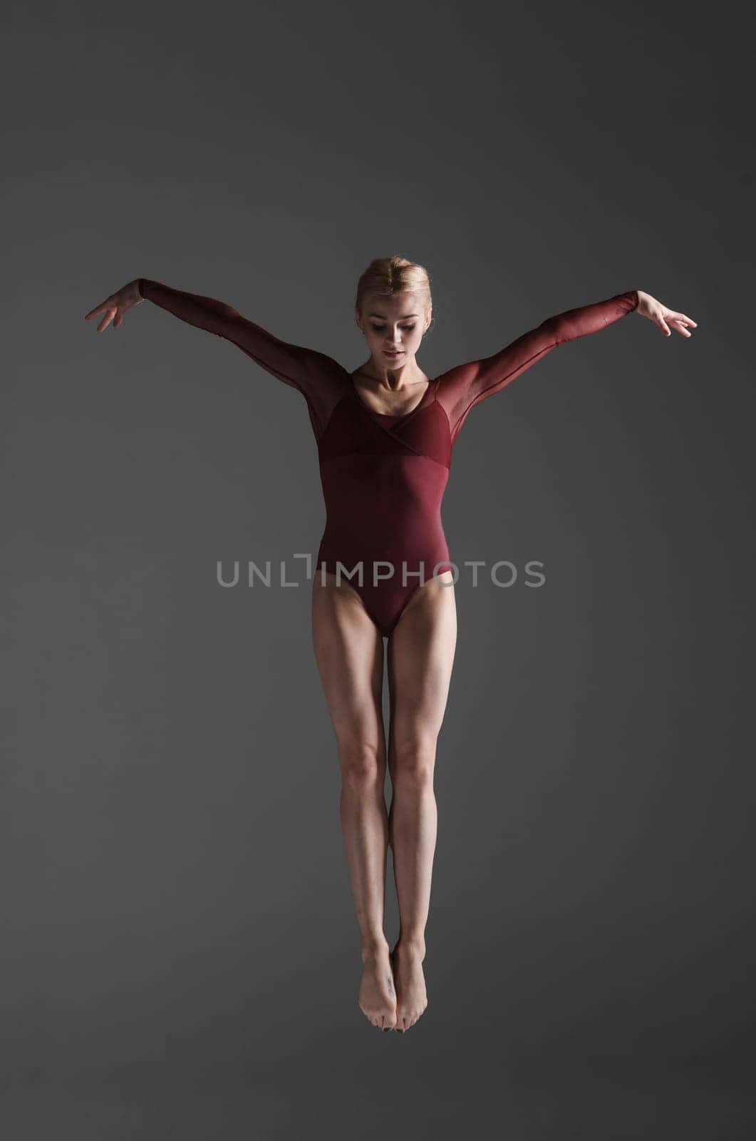 young beautiful modern style dancer jumping on a studio gray background
