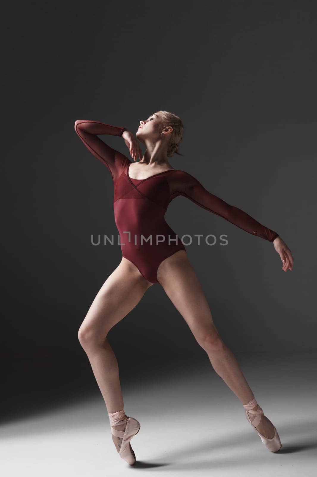 young beautiful modern style dancer posing on a studio gray background