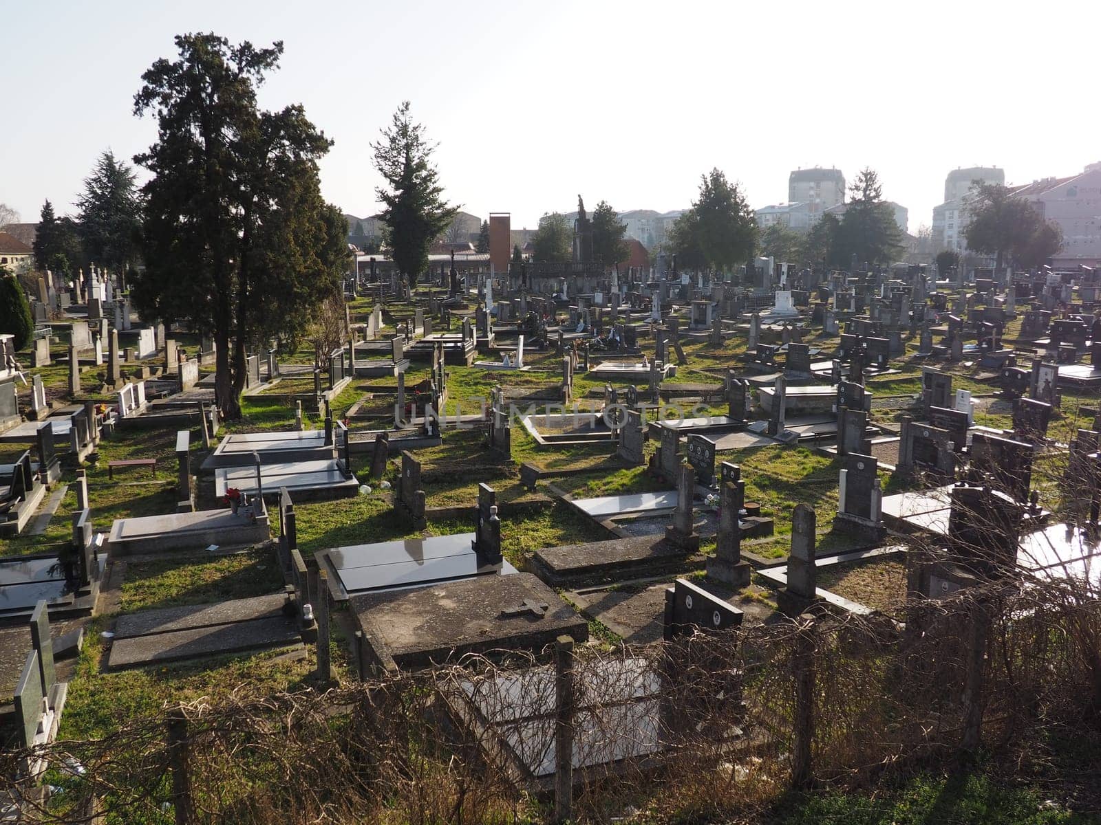 Sremska Mitrovica, Serbia, February 25, 2021. Christian city modern cemetery. Graves with stone monuments and crosses. Granite headstones. Crypt or chapel. Funeral or Halloween theme.