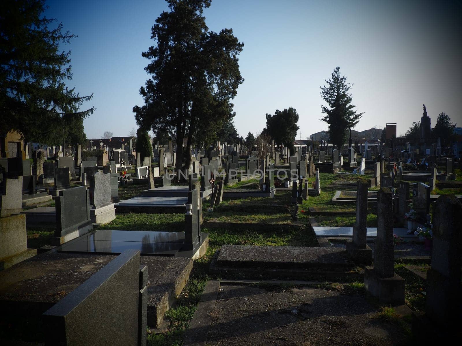 Sremska Mitrovica, Serbia, February 25, 2021. Christian city modern cemetery. Graves with stone monuments and crosses. Granite headstones. Crypt or chapel. Funeral or Halloween theme.