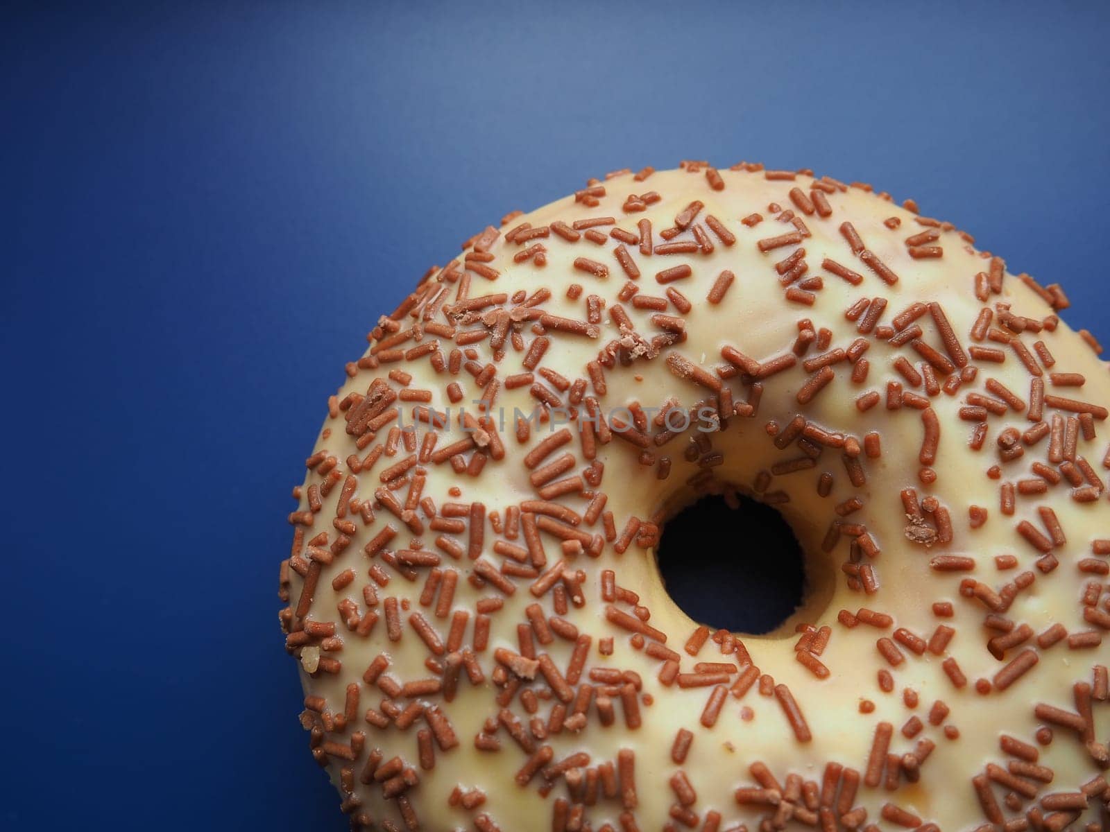 A doughnut or donut. A type of leavened fried dough. Sweet snack that can be homemade or purchased in bakeries, supermarkets, food stalls. Delicious pie with light icing on a blue background.