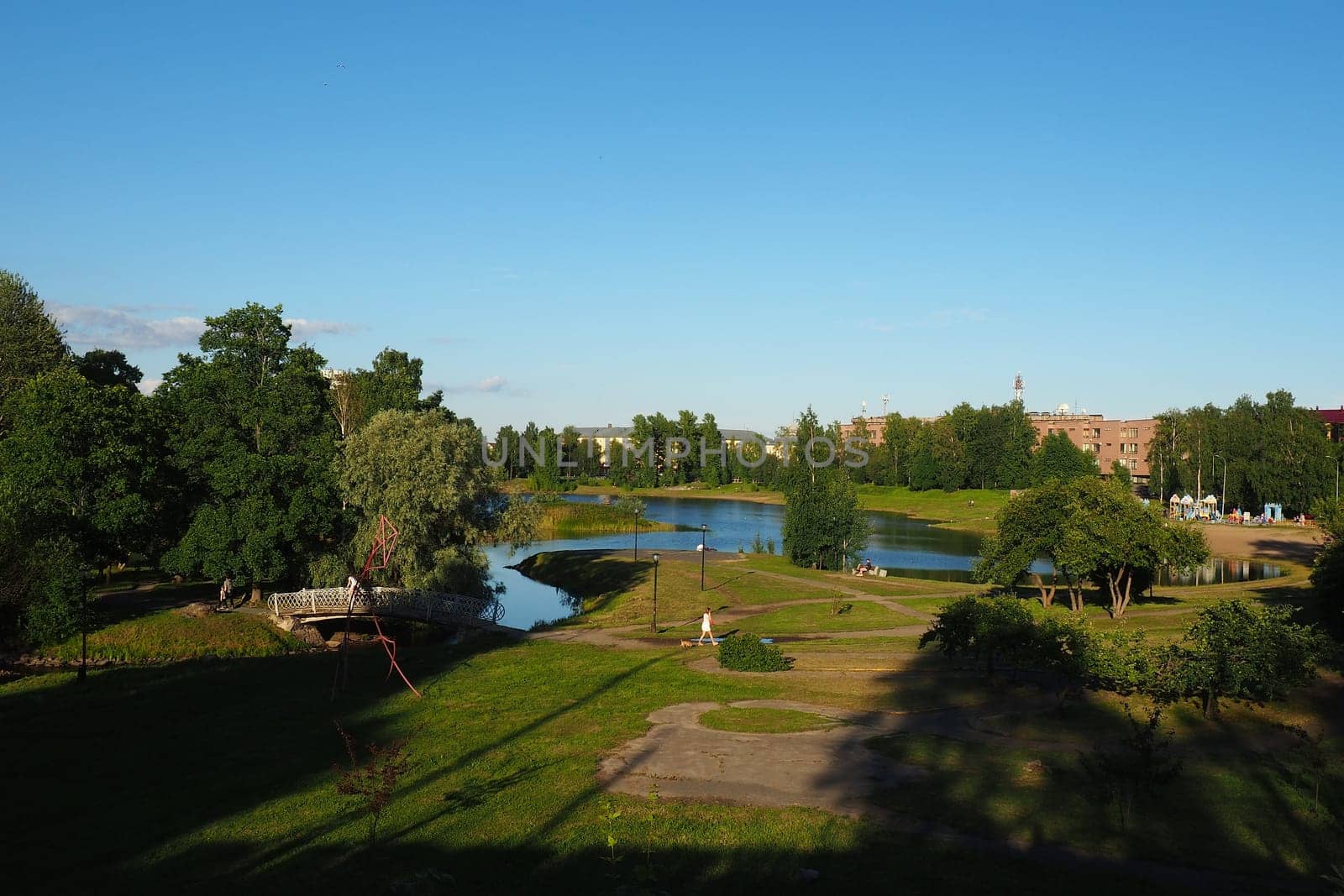 Mouth, floodplain and terraces of the Lososinka River, Petrozavodsk, Republic of Karelia August 3, 2022. Sunny windless evening. Bushes and trees. Passers-by people cross the river through the bridge
