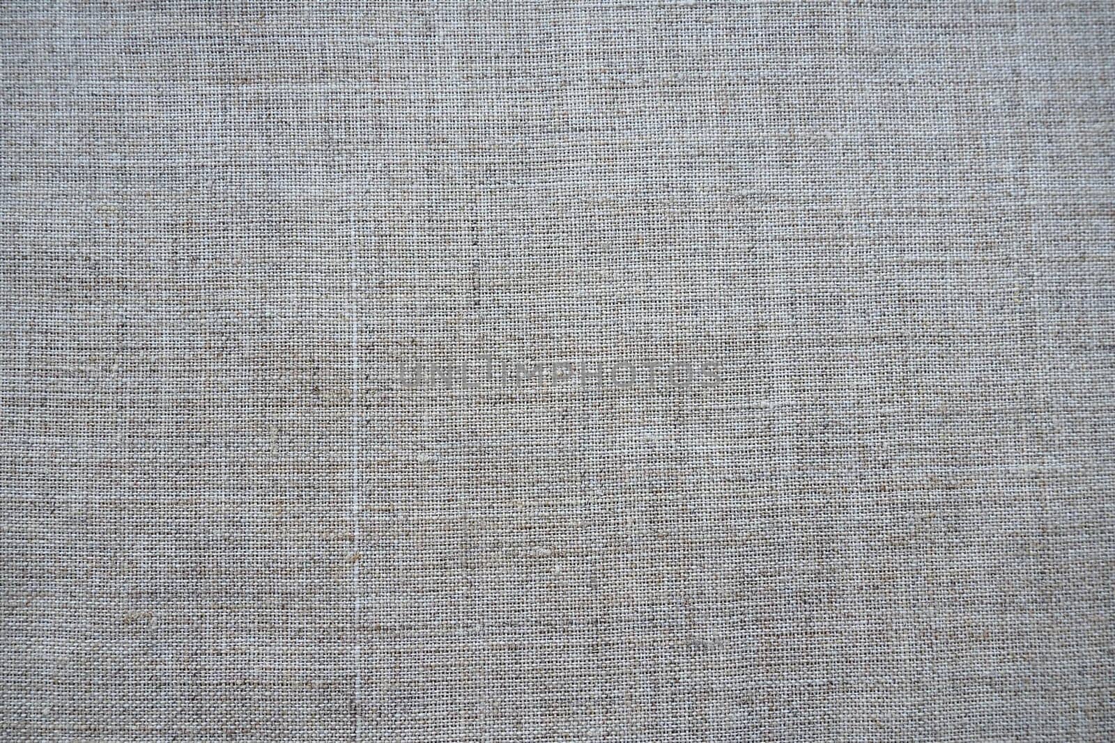 Fabric texture background. Gray fabric with weave. Natural slightly wrinkled look of the material. Uniform copy space background. Cotton, canvas or woolen thin fabric laid evenly on the surface