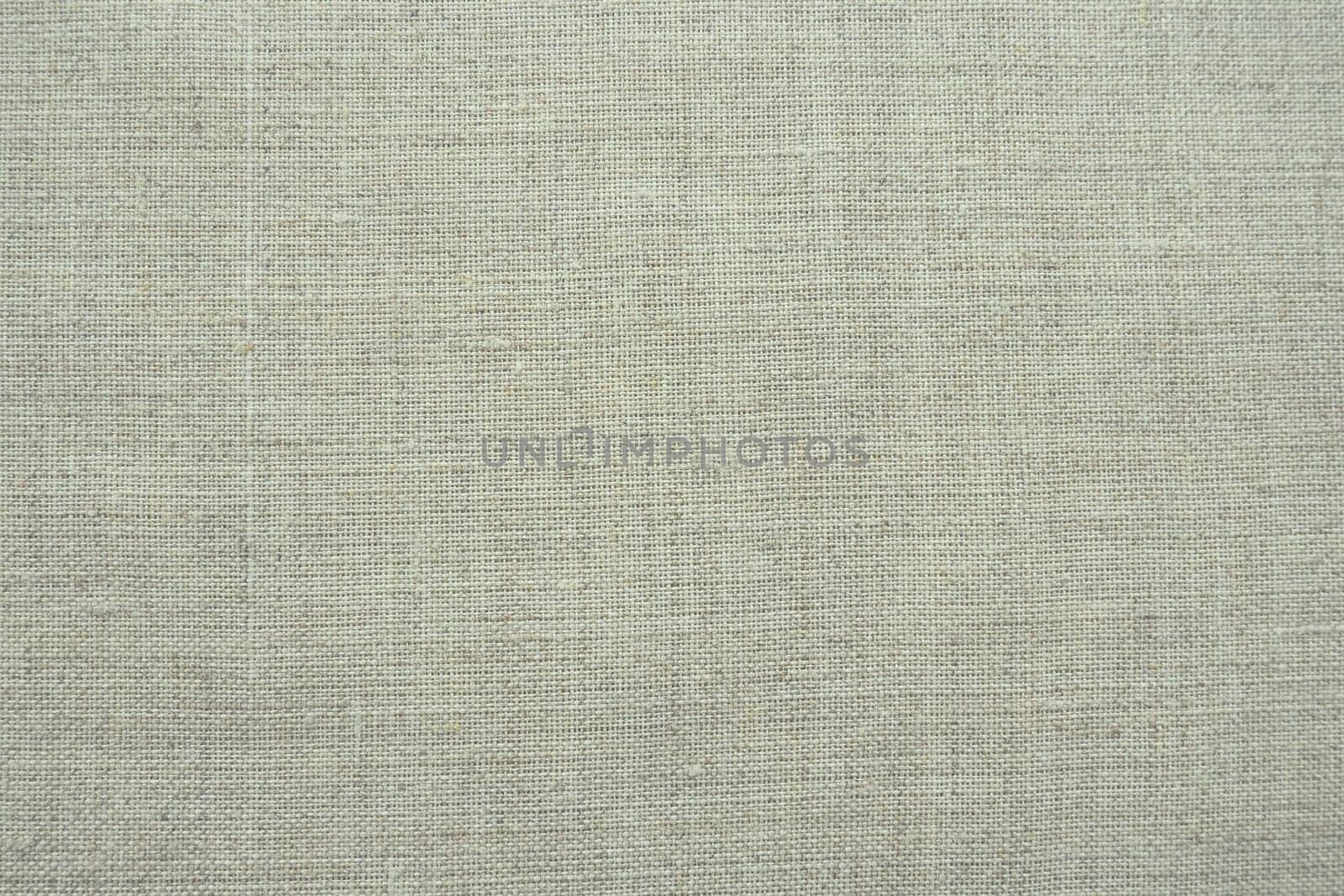 Fabric texture background. Light gray fabric with weave. Natural slightly wrinkled look of the material. Uniform copy space background. Cotton, canvas or woolen thin fabric laid evenly on the surface