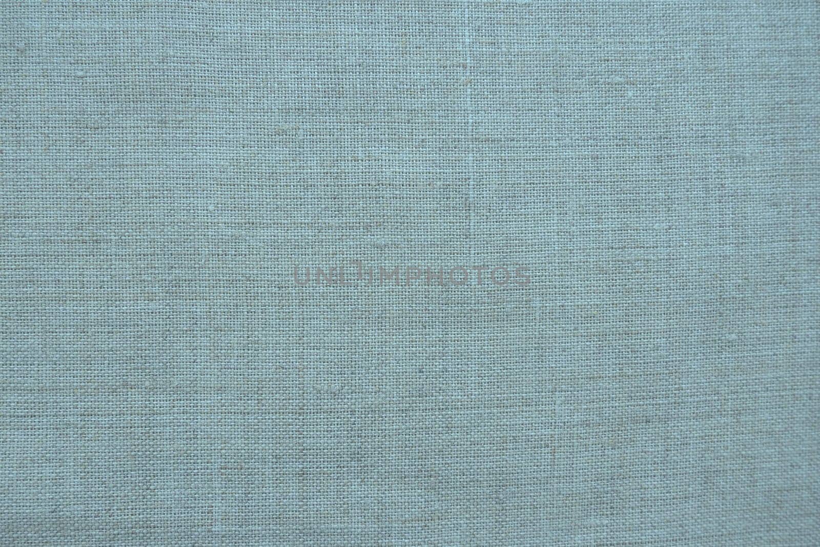 Fabric texture background. Blue fabric with weave. Natural slightly wrinkled look of the material. Uniform copy space background. Cotton, canvas or woolen thin fabric laid evenly on the surface