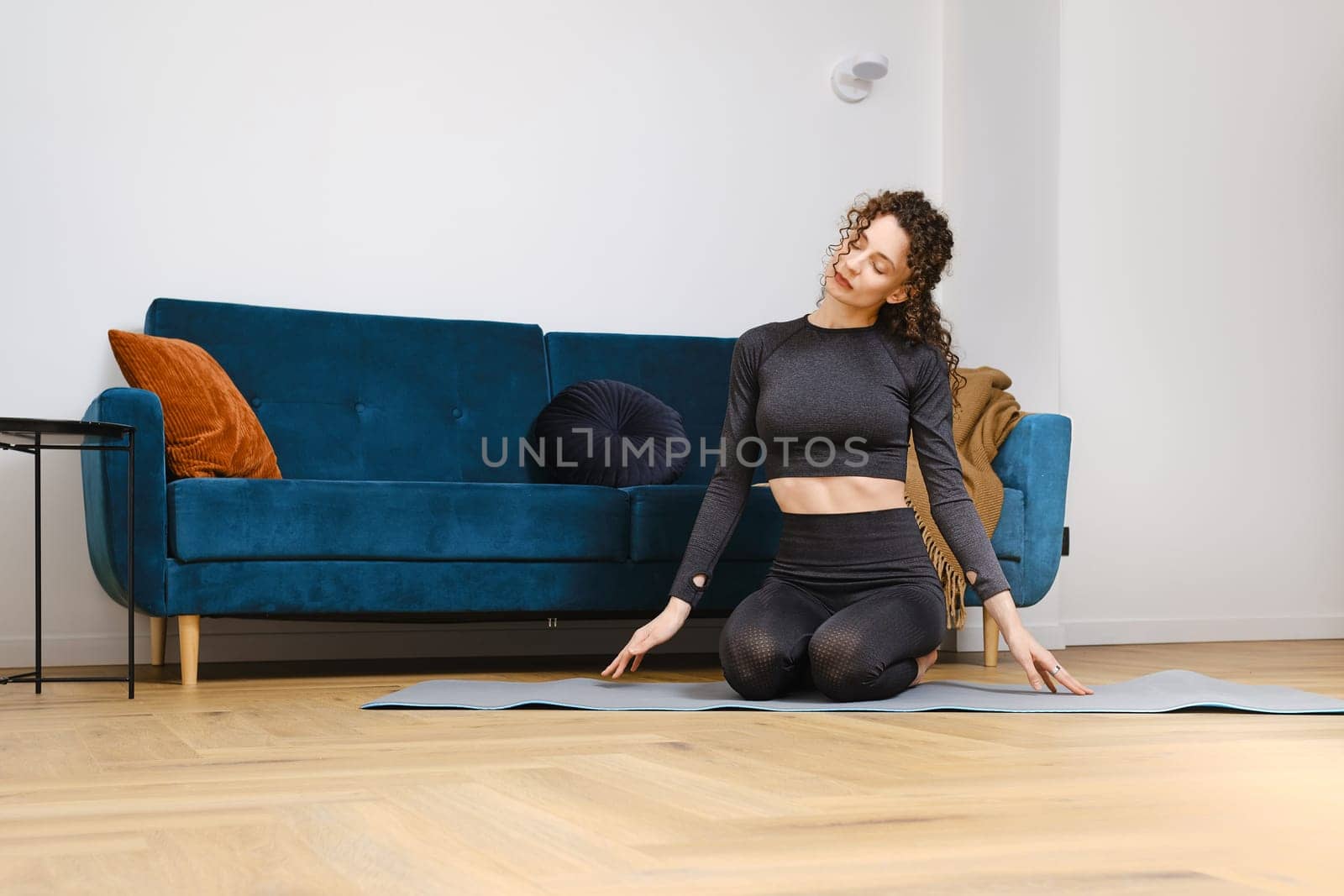 Young woman warming up neck muscles before doing fitness exercises at home