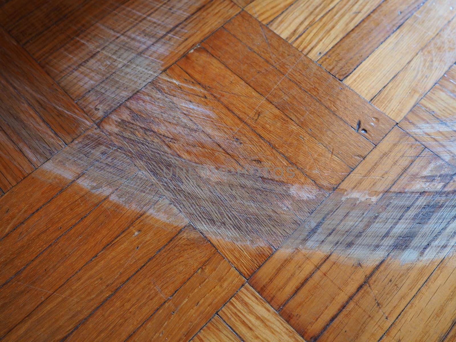Scratched parquet flooring in the room. Scratches, chips and dents on the floor. Parquet in need of repair