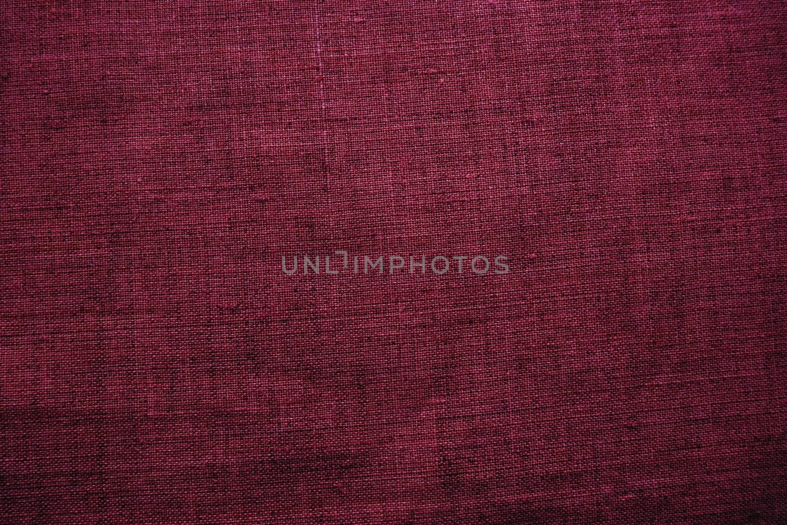 Fabric texture background. Burgundy purple fabric with weave. Natural slightly wrinkled look of the material. Uniform copy space background. Cotton, canvas or woolen thin fabric laid on the surface
