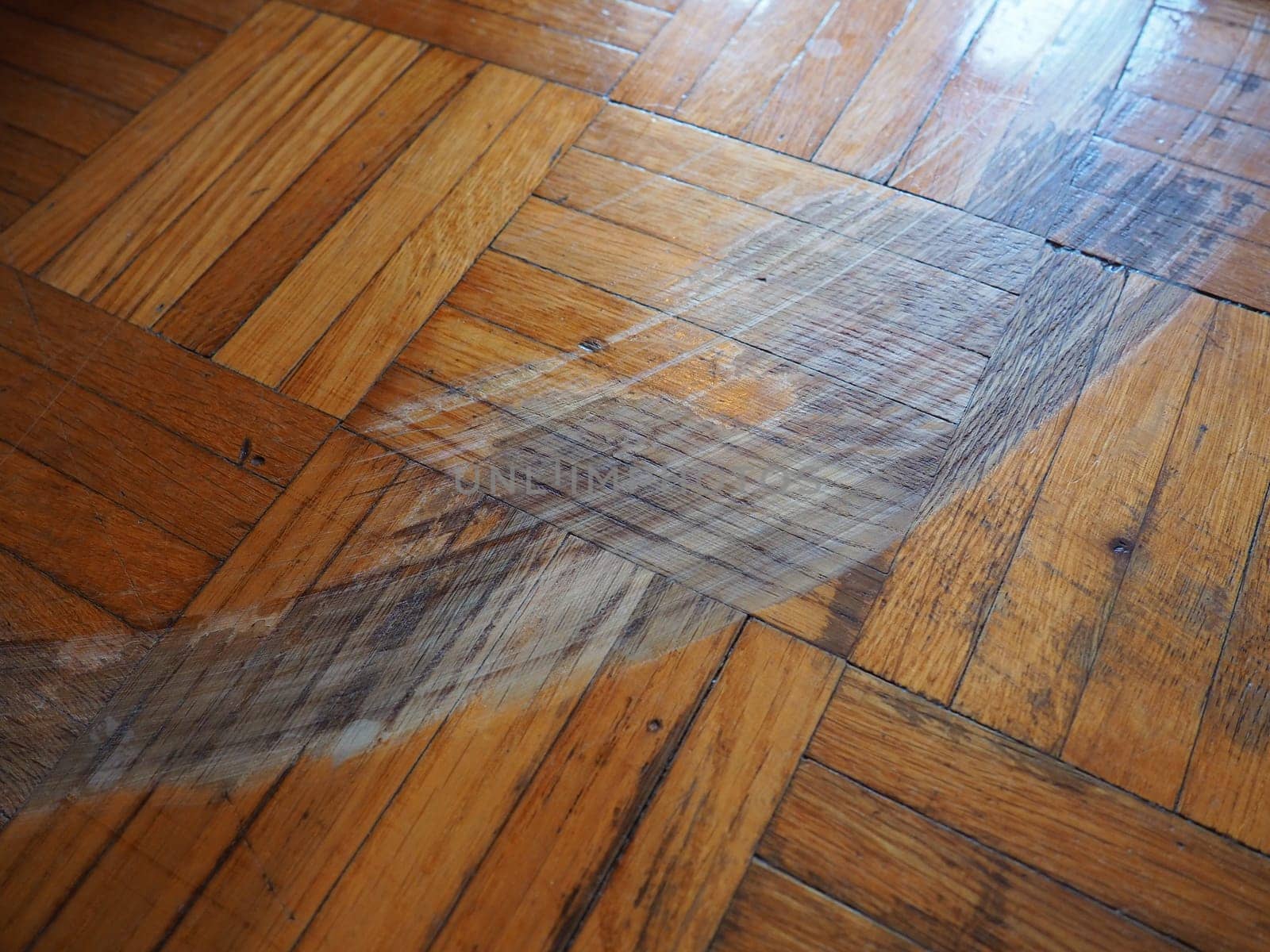 Scratched parquet flooring in the room. Scratches, chips and dents on the floor. Parquet in need of repair