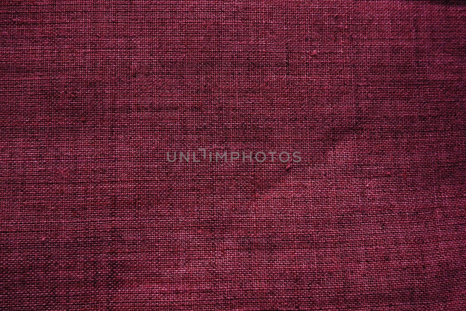 Fabric texture background. Burgundy purple fabric with weave. Natural slightly wrinkled look of the material. Uniform copy space background. Cotton, canvas or woolen thin fabric laid on the surface