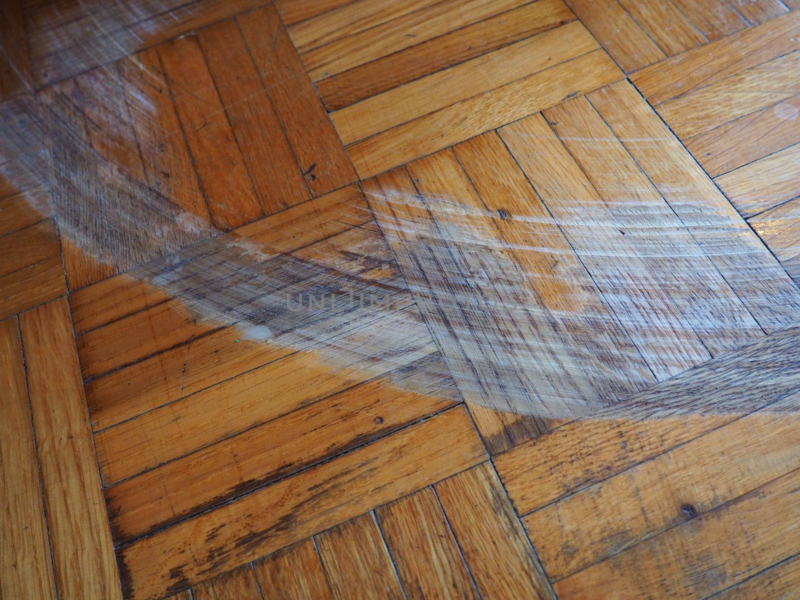 Scratched parquet flooring in the room. Scratches, chips and dents on the floor. Parquet in need of repair