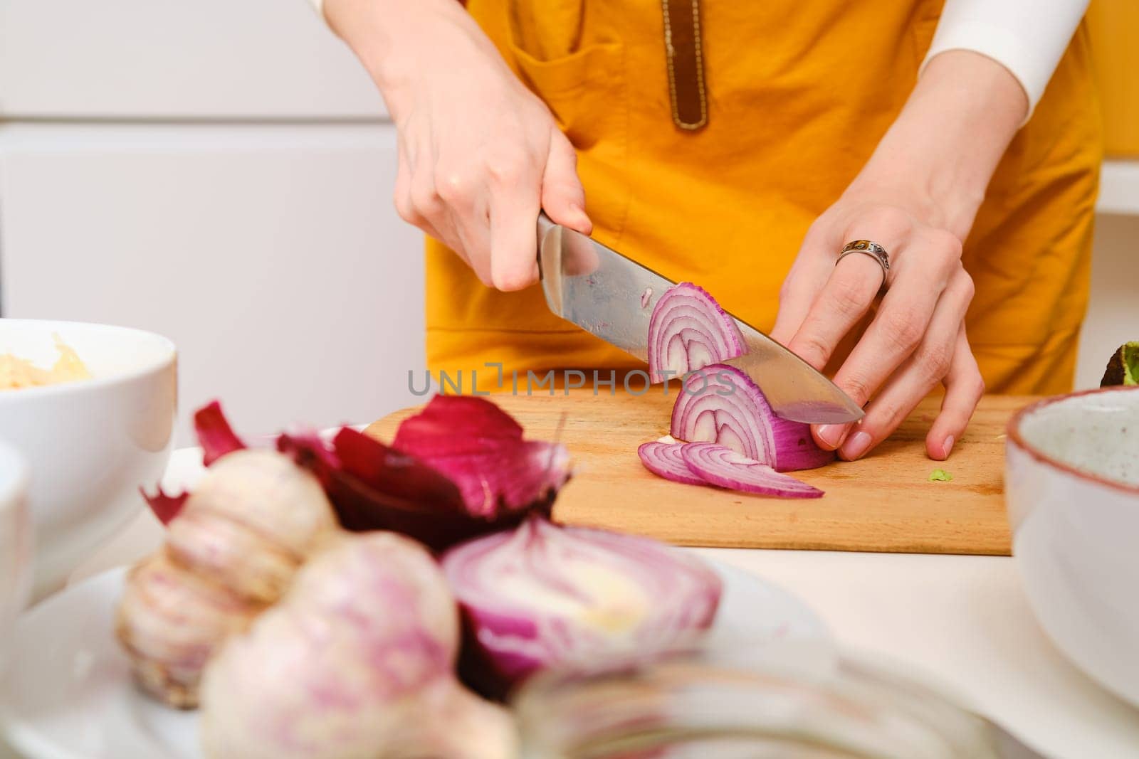 Closeup view of female hands cutting onion into slices