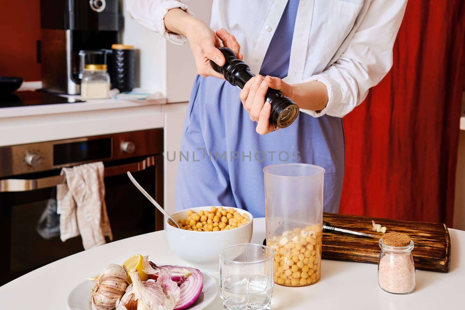 Closeup view of adding pepper into blender with chickpeas while making hummus
