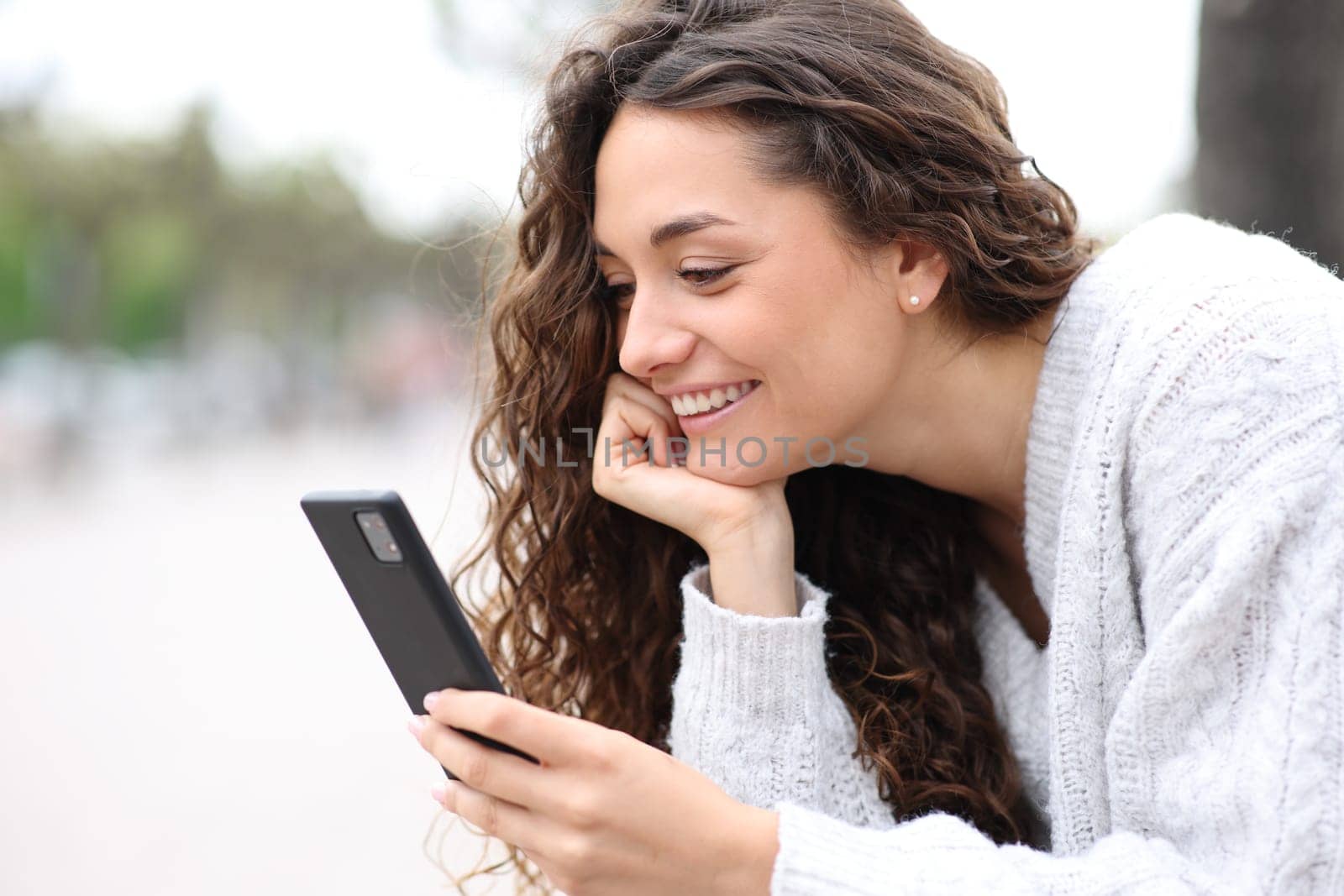 Happy woman using cell phone outdoors in the street