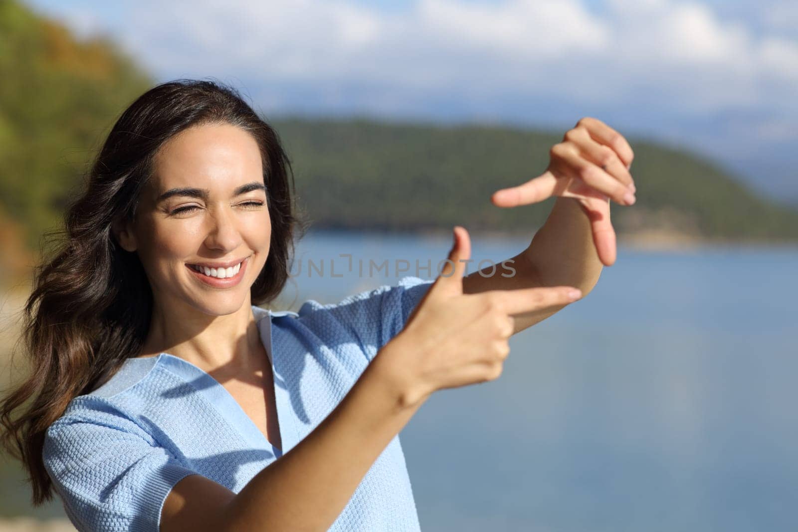 Happy woman framing with hands calculating perspective in a mountain lake