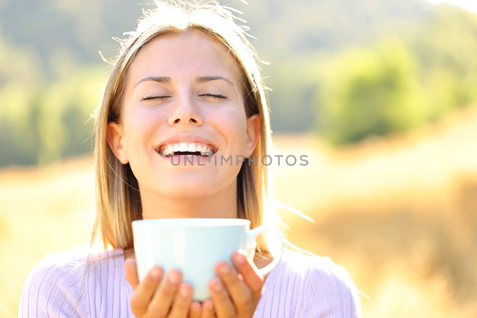 Front view portrait of a happy teen breathing fresh air holding coffee cup in the mountain