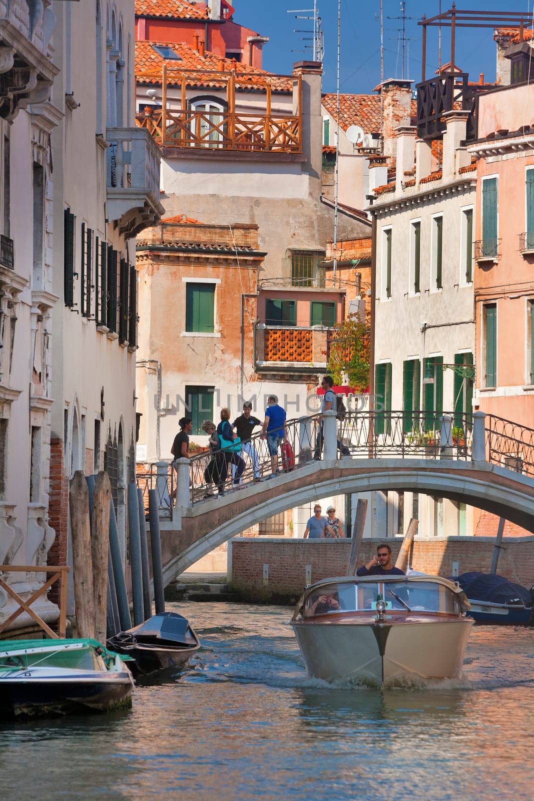 Boaters motor down the many canals of Venice, Italy on a hot summer day.